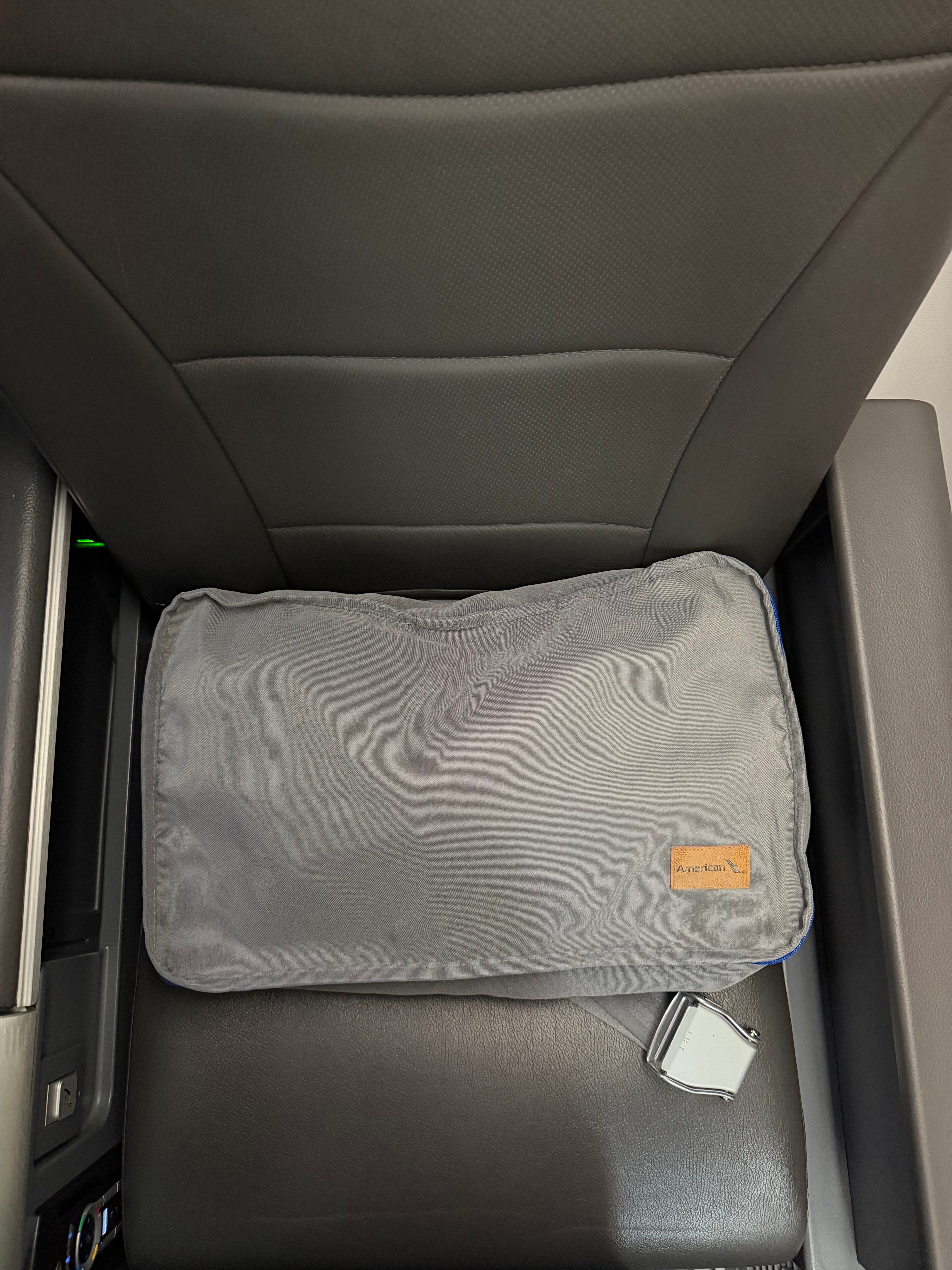 Gray pillow placed on an American Airlines Main Cabin Extra seat.