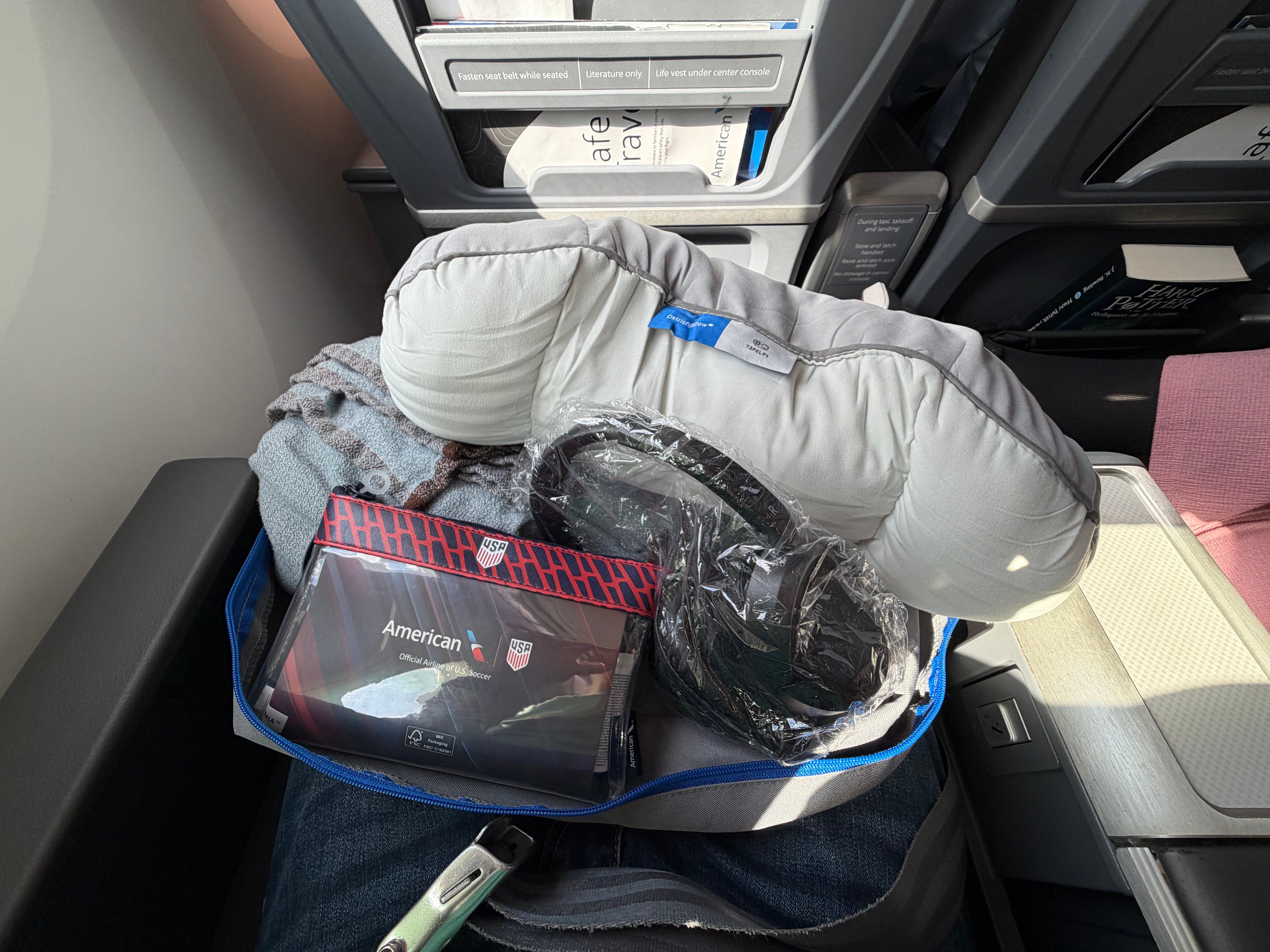 Pillow, blanket, headphones, and amenity kit inside the Main Cabin Extra welcome bag.
