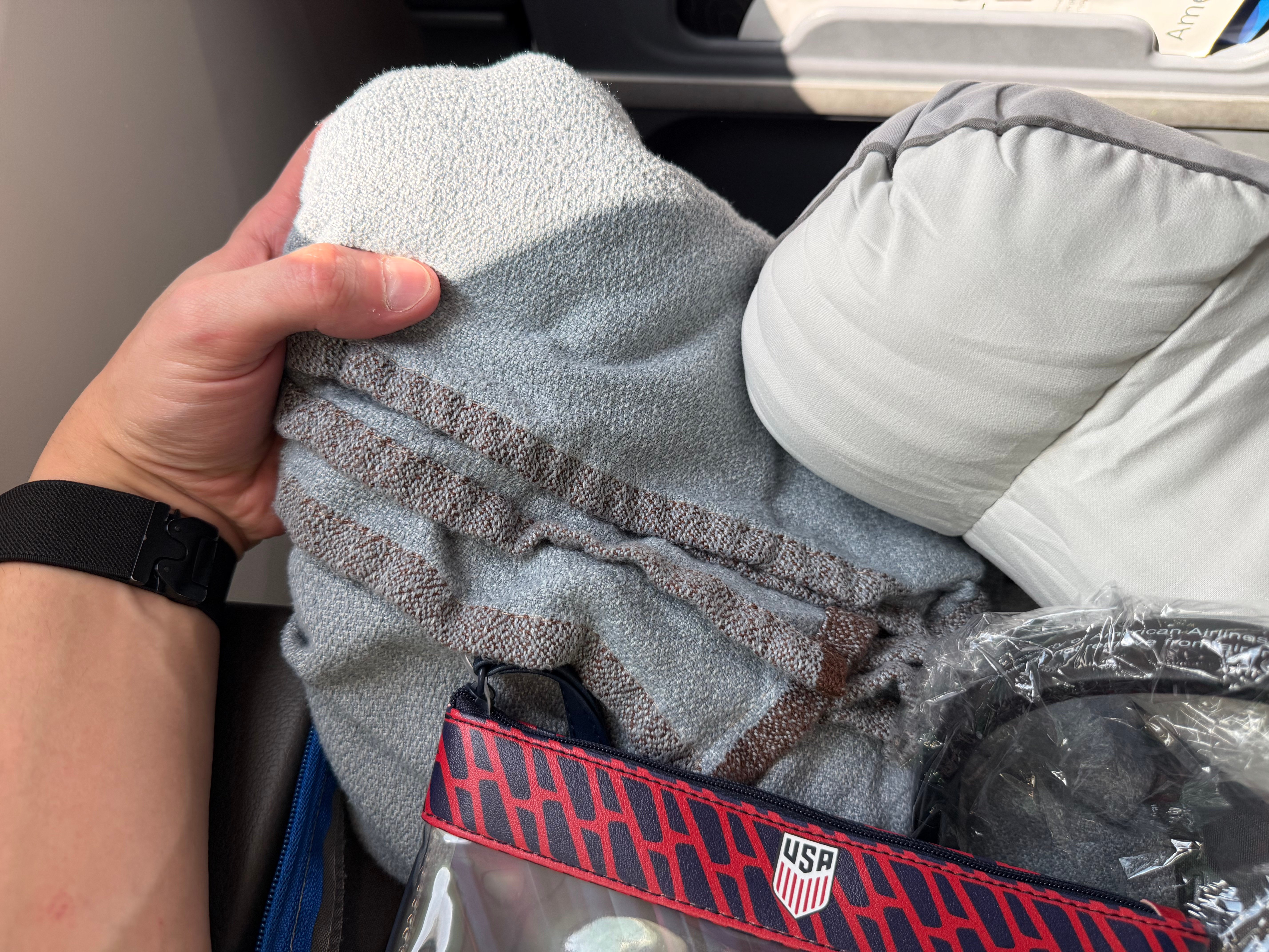 Gray blanket and pillow provided at the Main Cabin Extra seat.