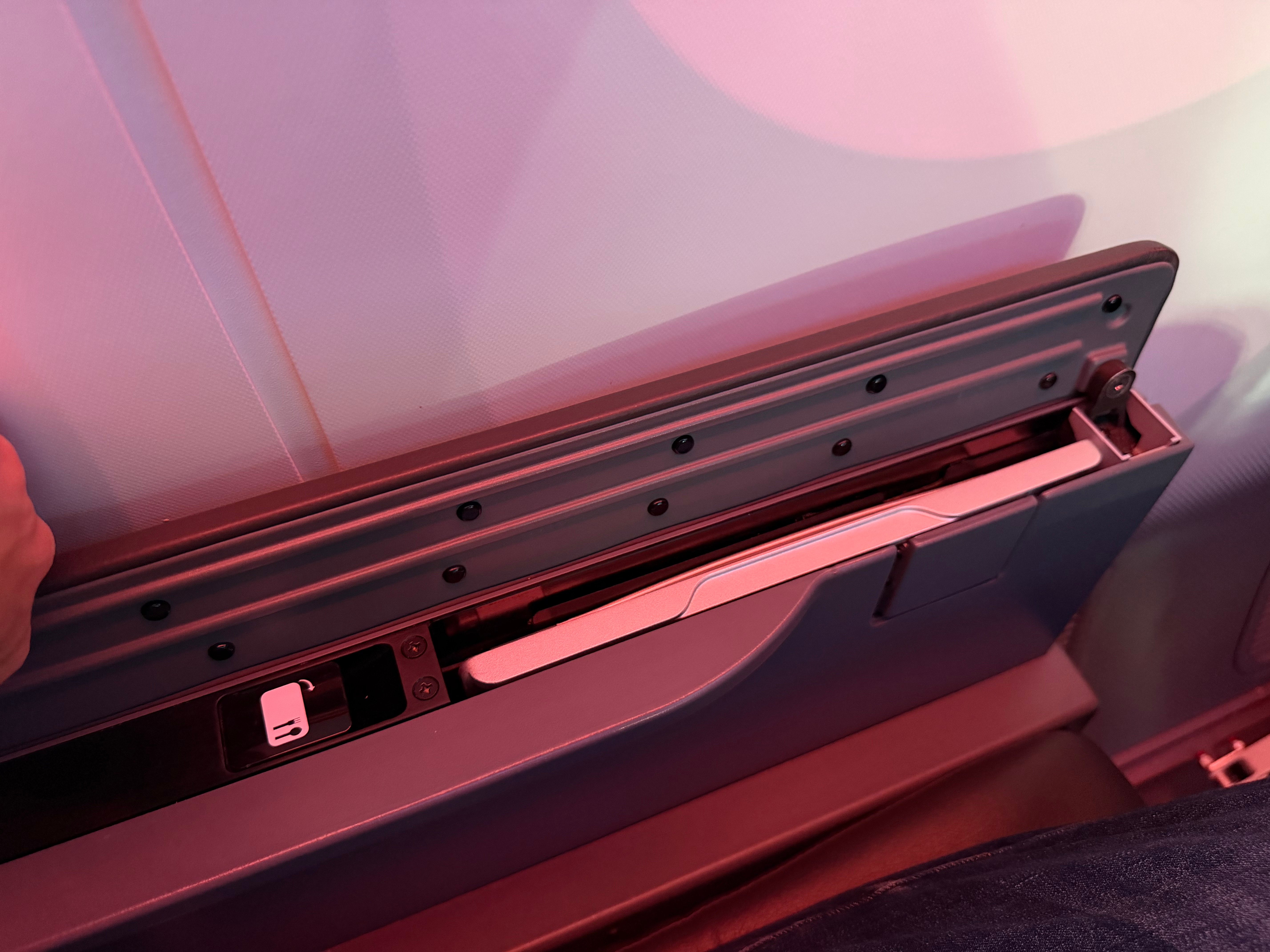 Tray table stored inside the armrest of an American Main Cabin Extra seat.