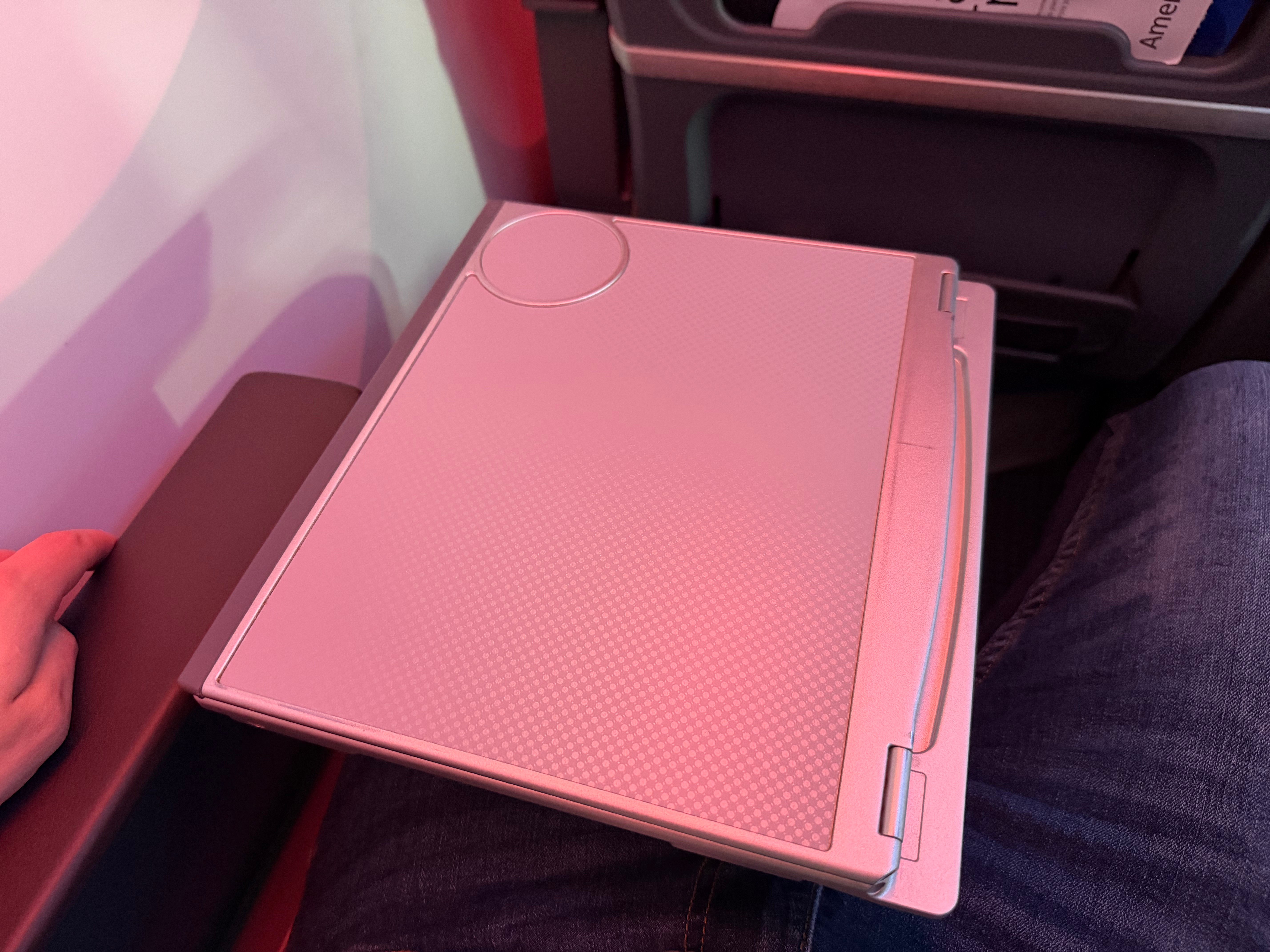 Tray table being opened from the Main Cabin Extra armrest.