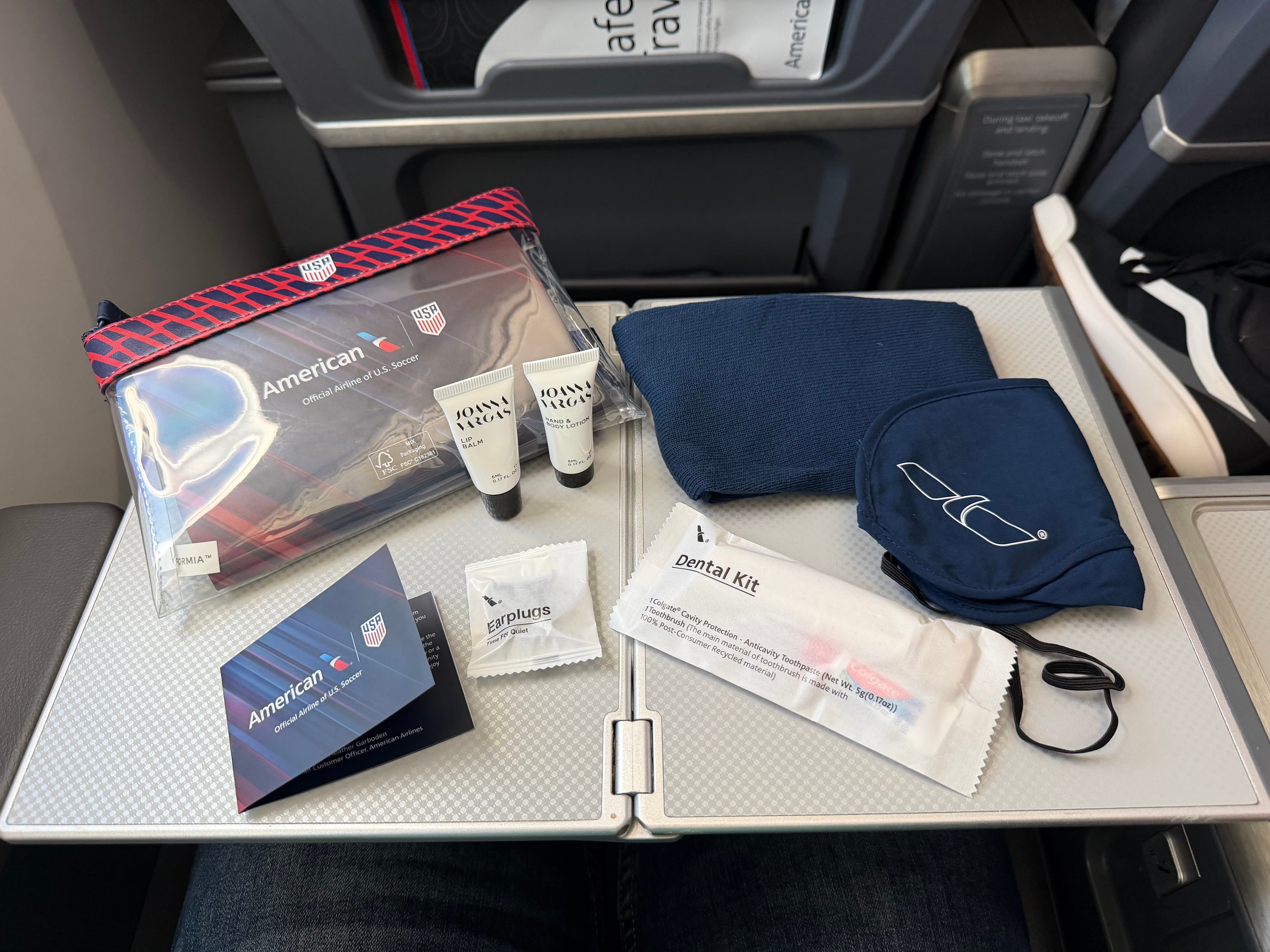 Contents of the American Airlines U.S. Soccer amenity kit, including an eye mask, dental kit, earplugs, lip balm, and lotion.