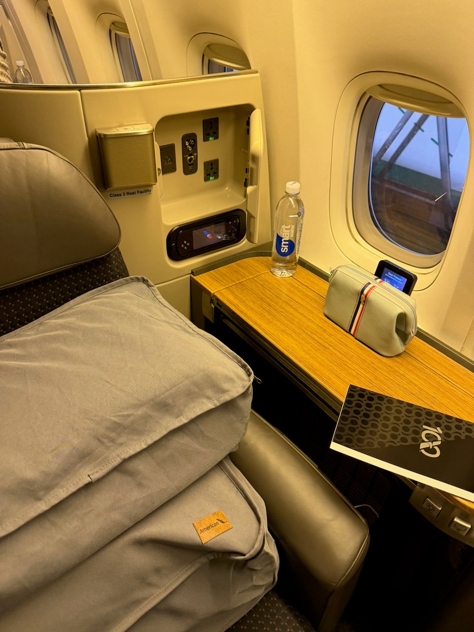 Wood-veneer side table and blankets at the Flagship First seat.