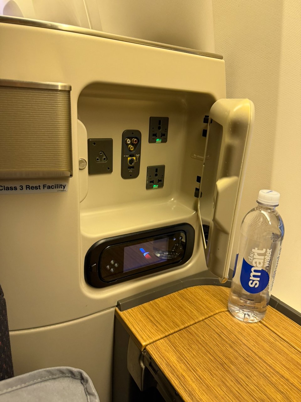 Seat power outlet and bottled water at the American Flagship First suite.