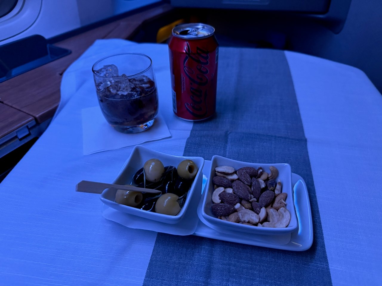 Warmed nuts and olives with a drink in American Flagship First.