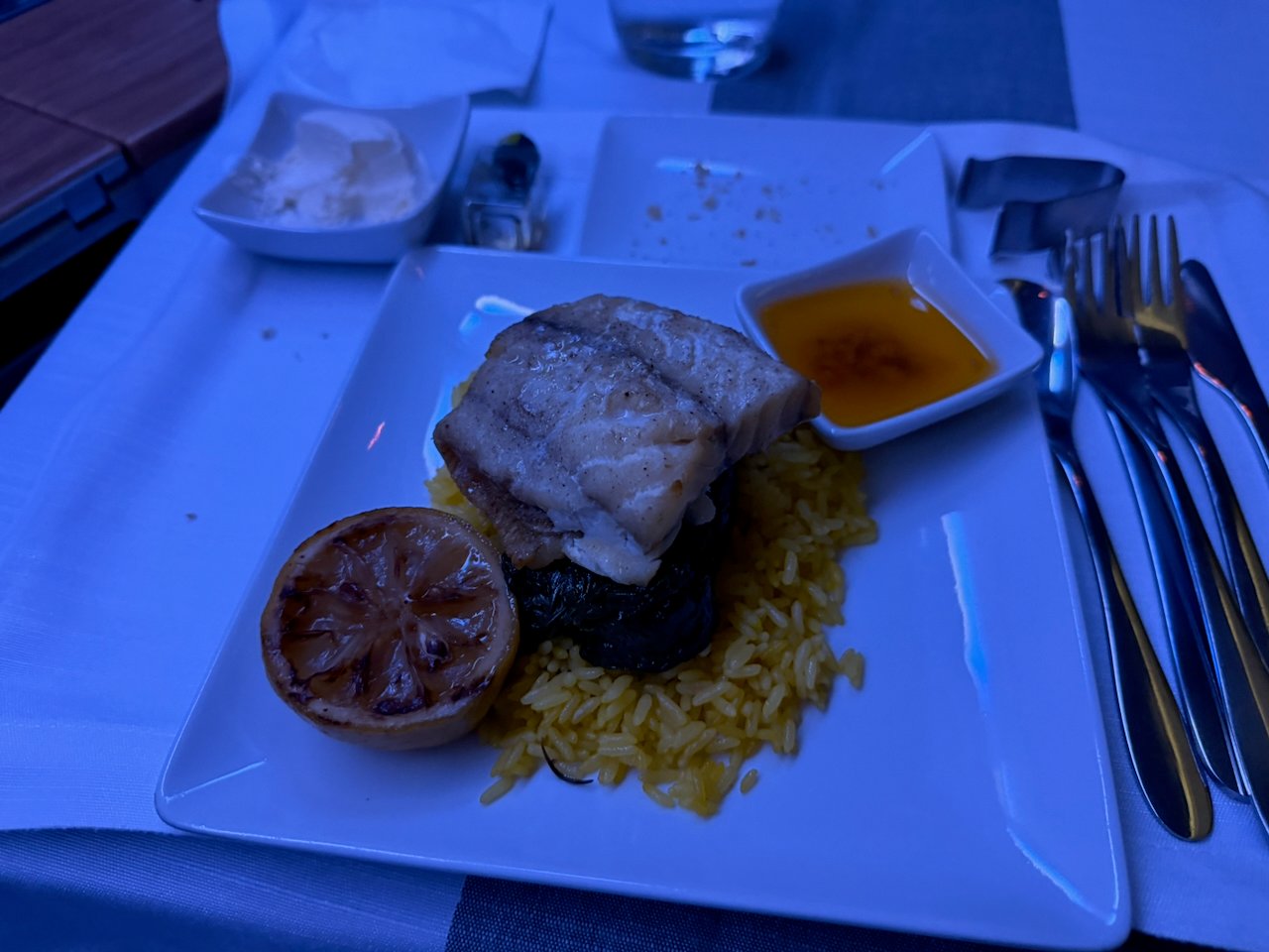 Pan-seared congrio with saffron rice and grilled lemon in Flagship First.