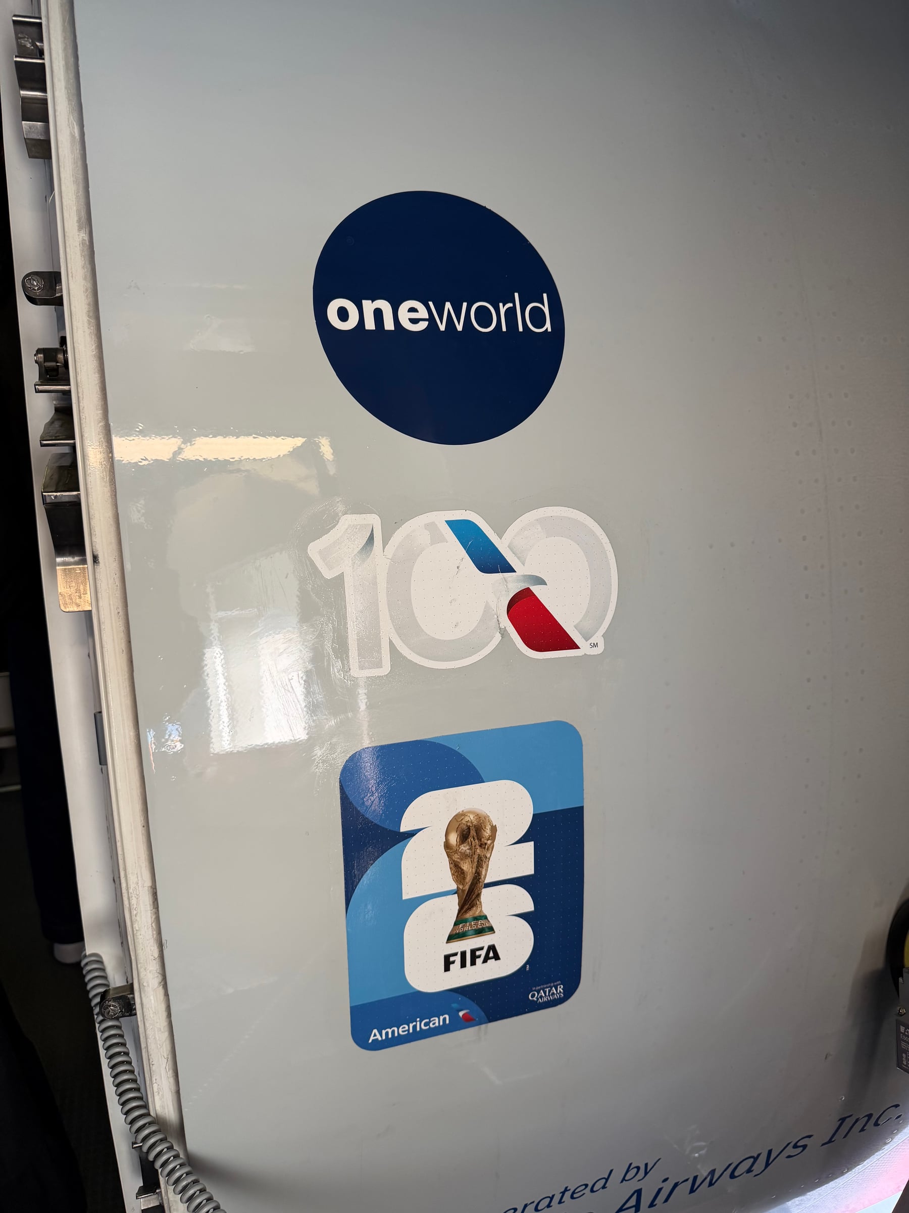 oneworld, American Airlines centennial, and FIFA World Cup 2026 decals on the aircraft door.
