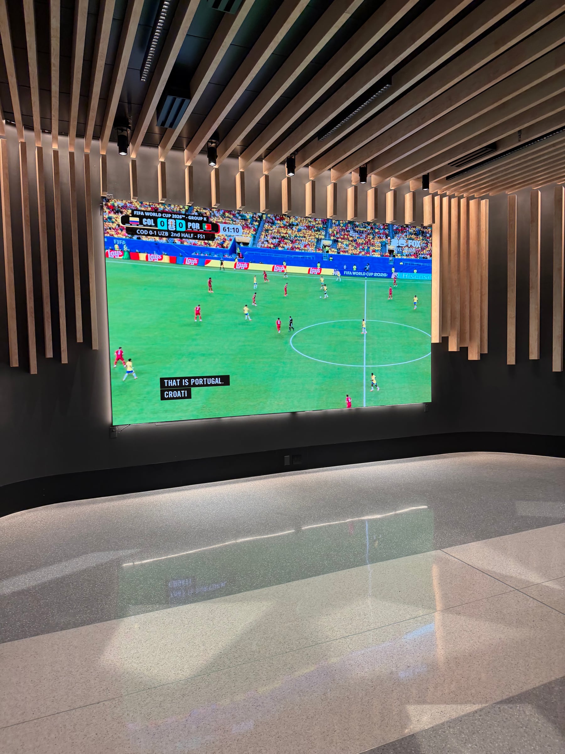 Large screen showing a FIFA World Cup match inside JFK Terminal 8.