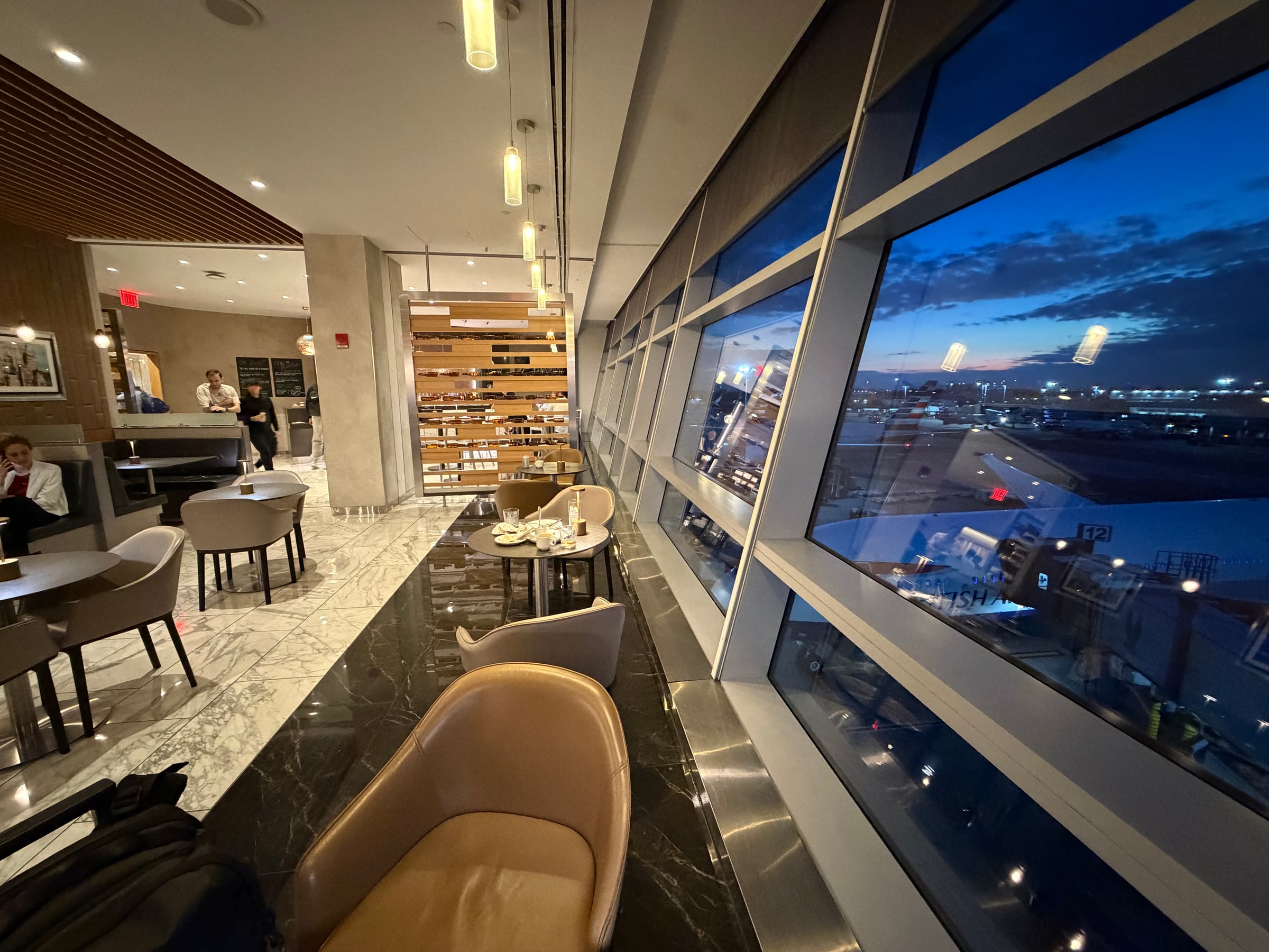 Window seating and dining tables overlooking the runway in the Greenwich Lounge.