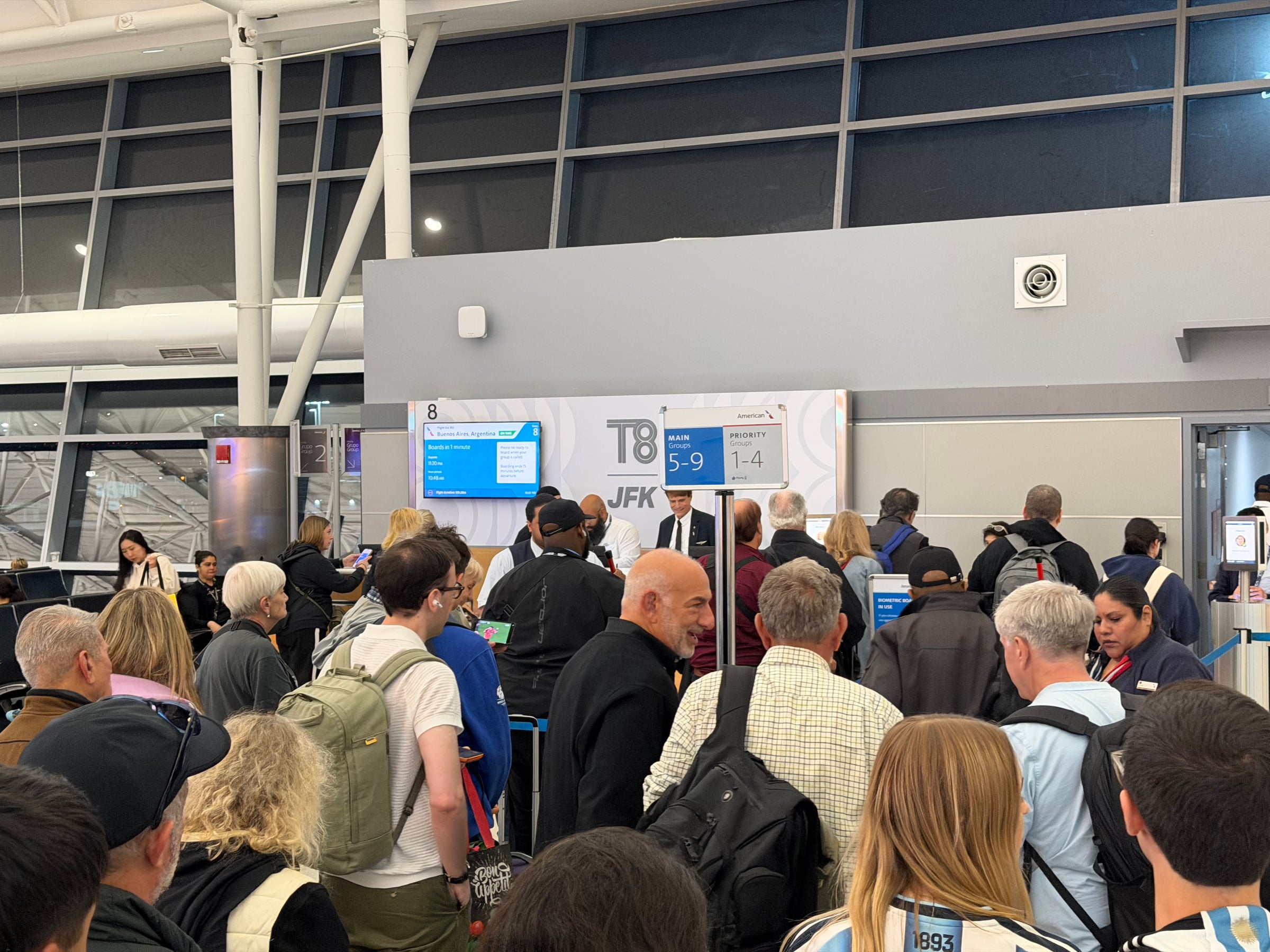 Crowded boarding area at JFK gate 8 for American Airlines flight AA953 to Buenos Aires.