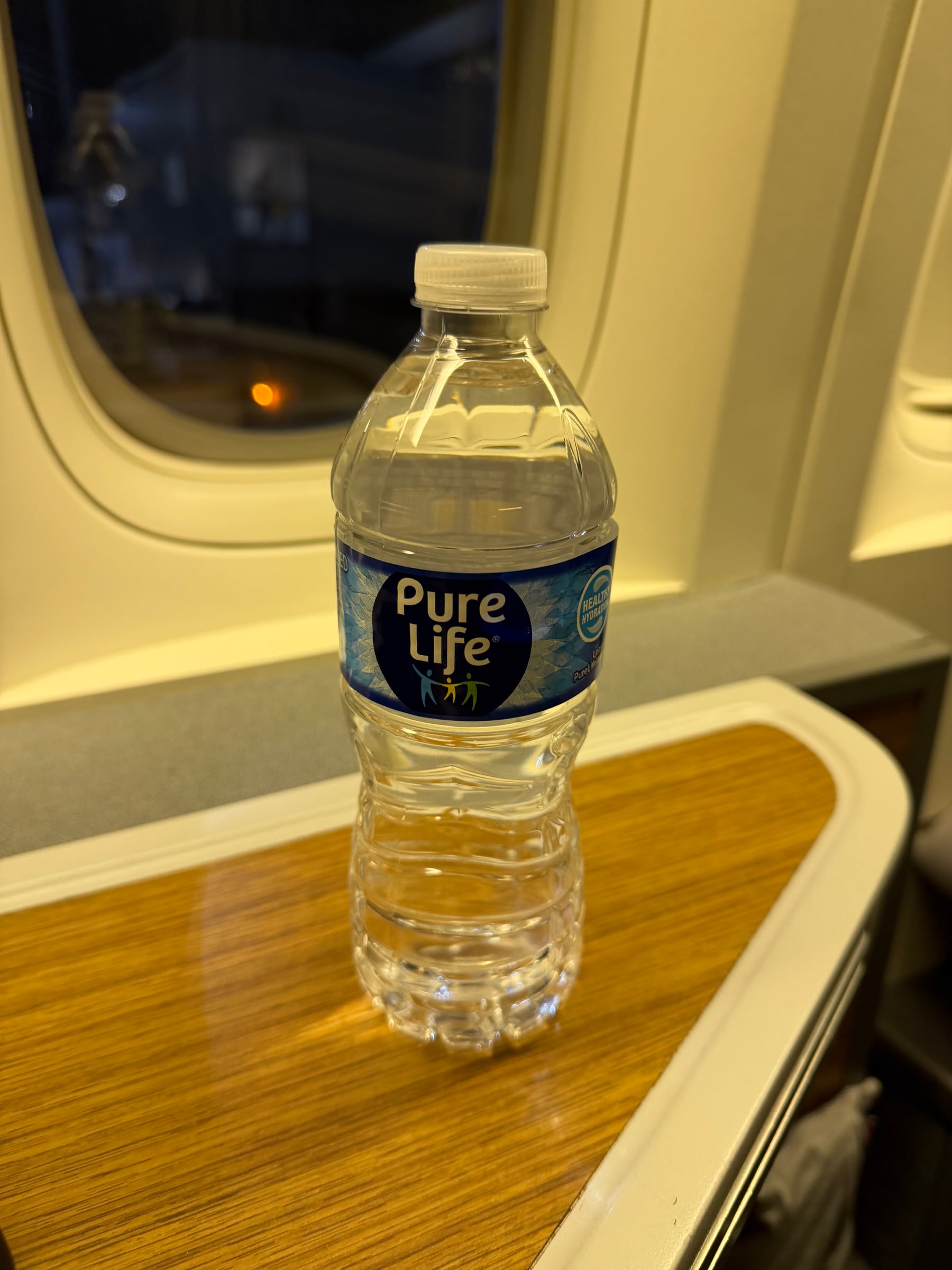 Bottle of water on the side table at the American Airlines Business Class seat.