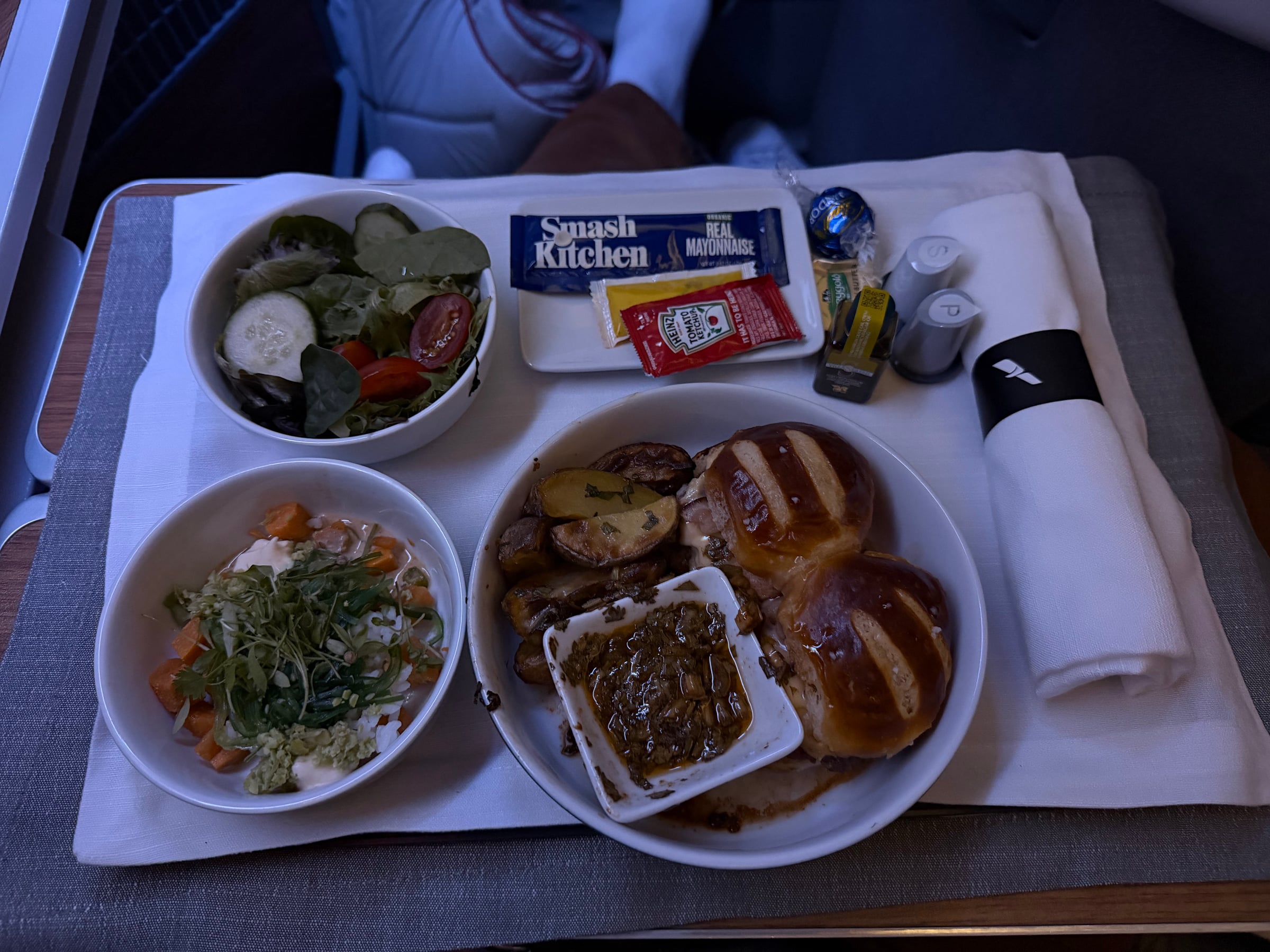 Full dinner tray with centennial sliders, salads, and bread in American Flagship Business.