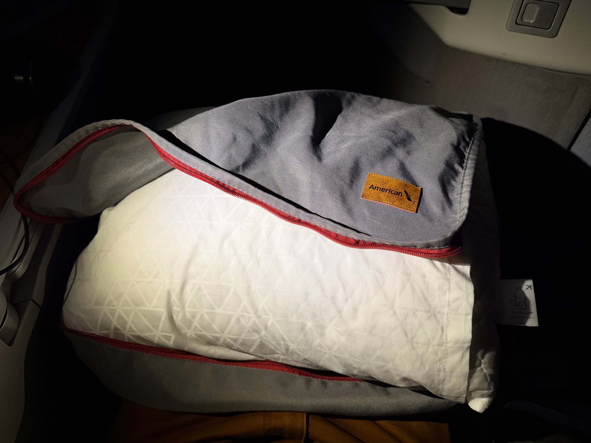 Pillow and blanket arranged for sleeping in American Airlines Flagship Business.