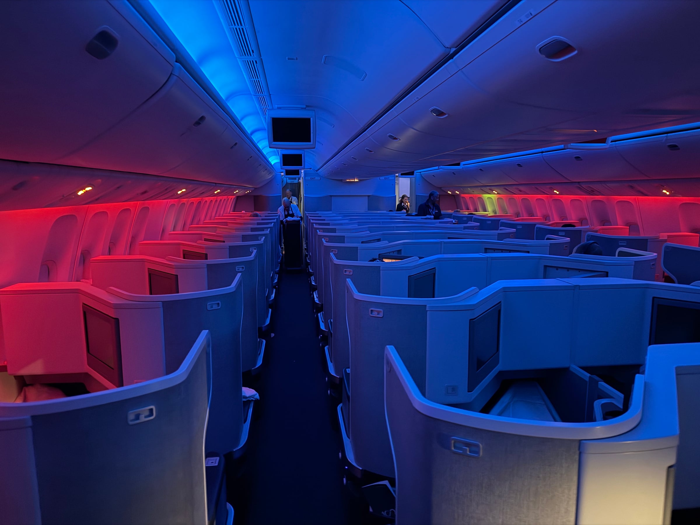 American 777 Business Class cabin illuminated with red and blue mood lighting.