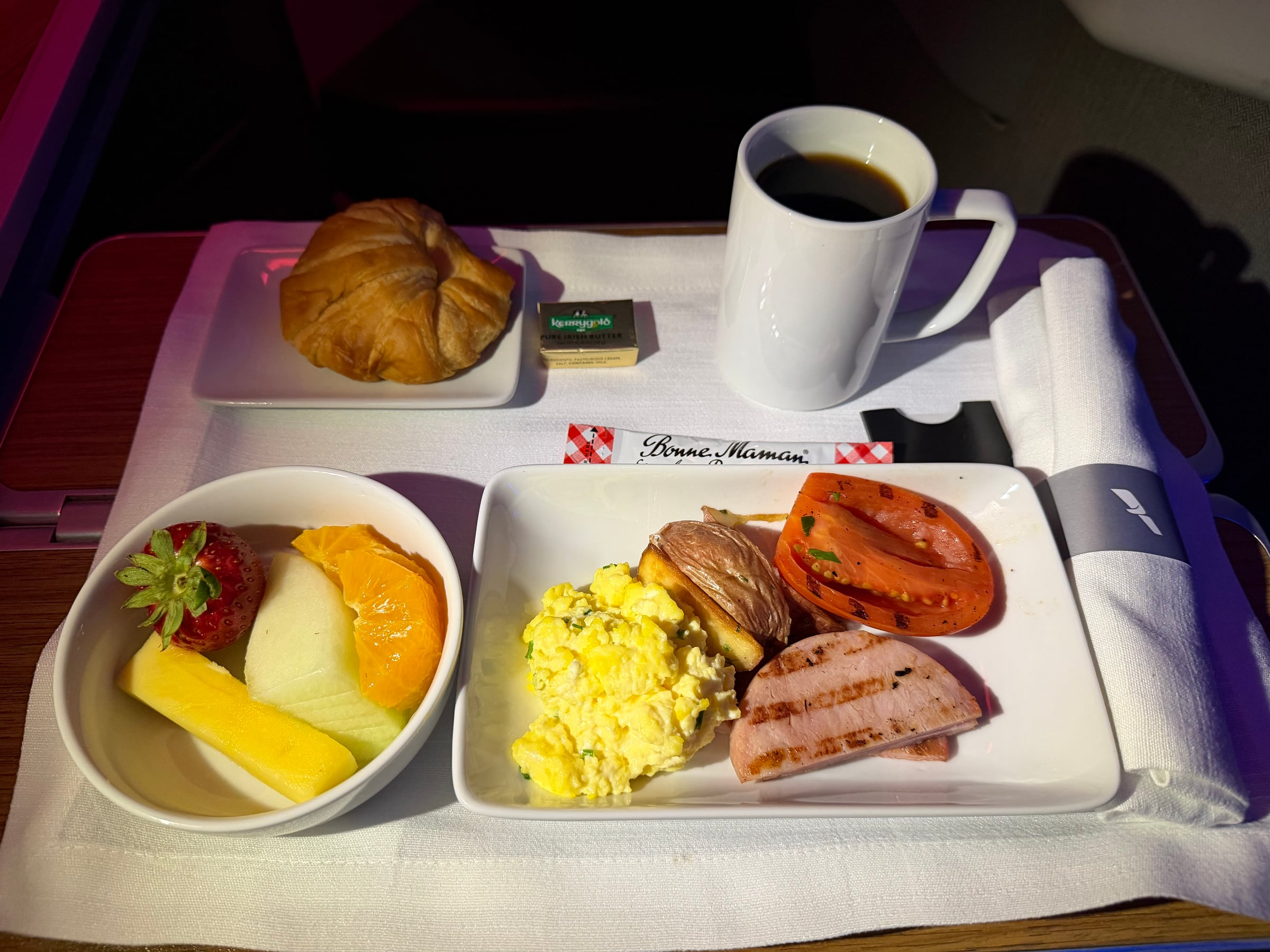 American Airlines Business Class breakfast tray with eggs, fruit, croissant, and coffee.