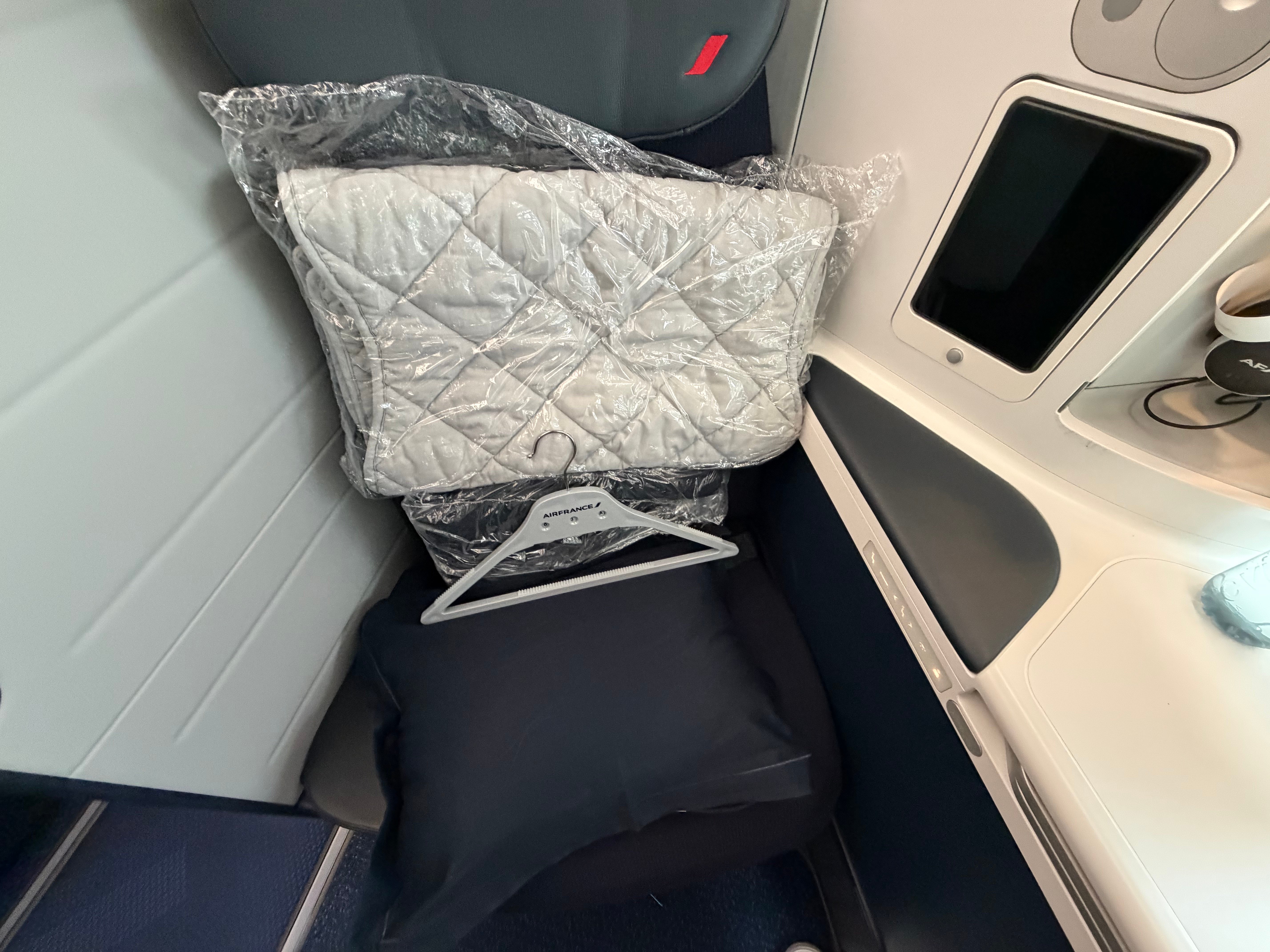Bedding and slippers laid out on the Business Class seat.