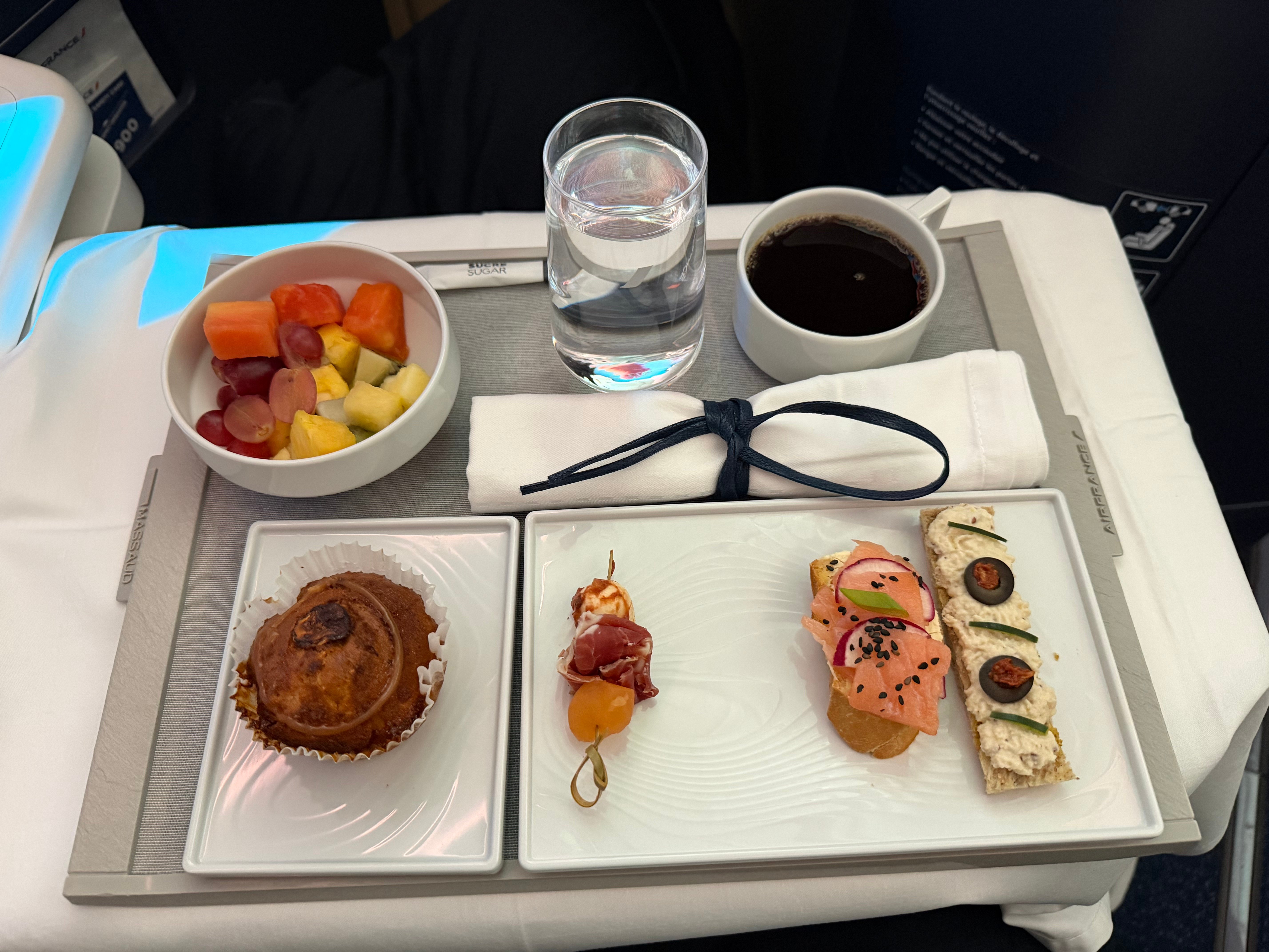 Light meal before arrival with small savory items, fruit, and a muffin.