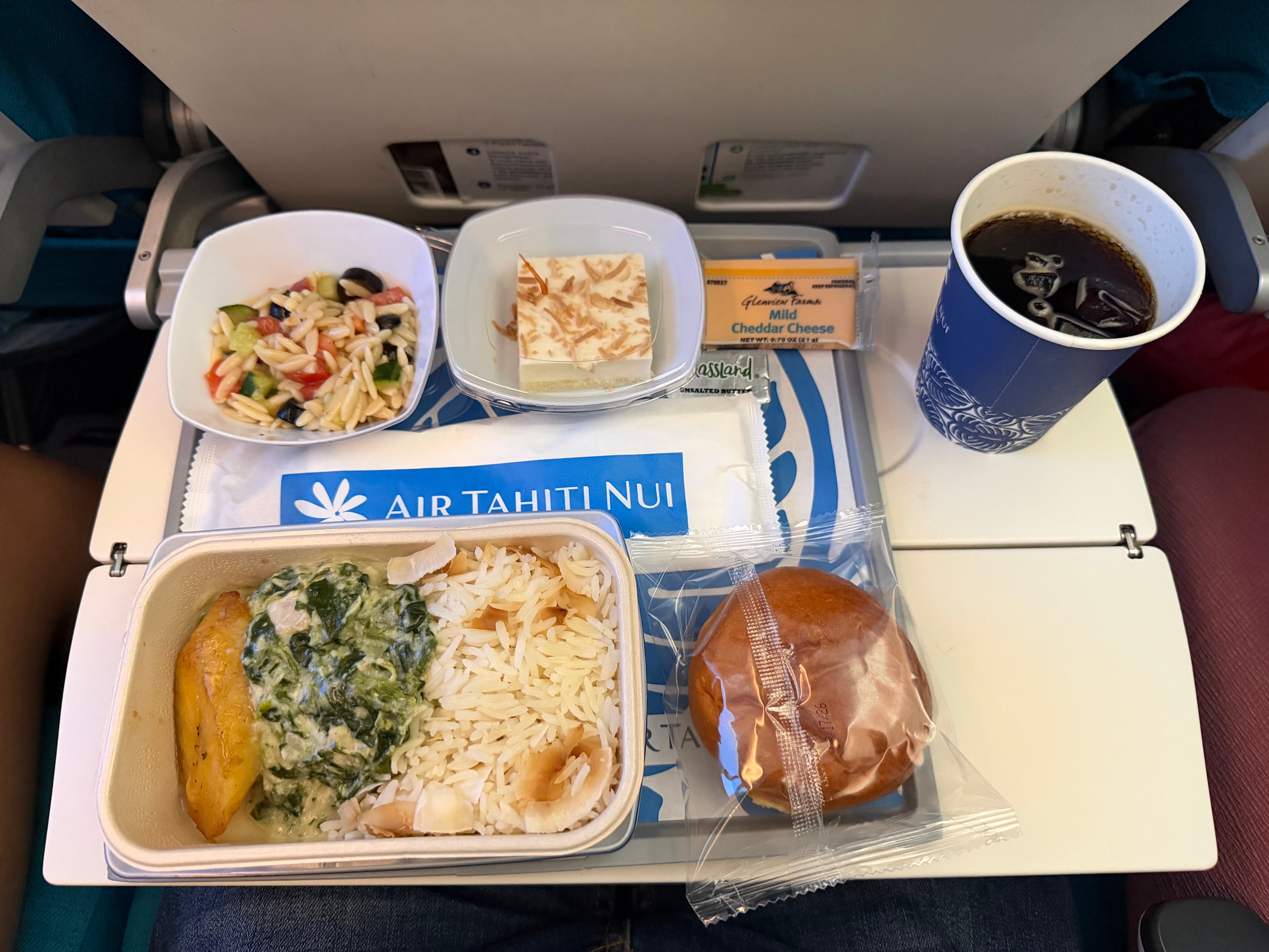 Air Tahiti Nui Economy dinner with chicken, rice, pasta salad, bread, cheese, and coconut cake.