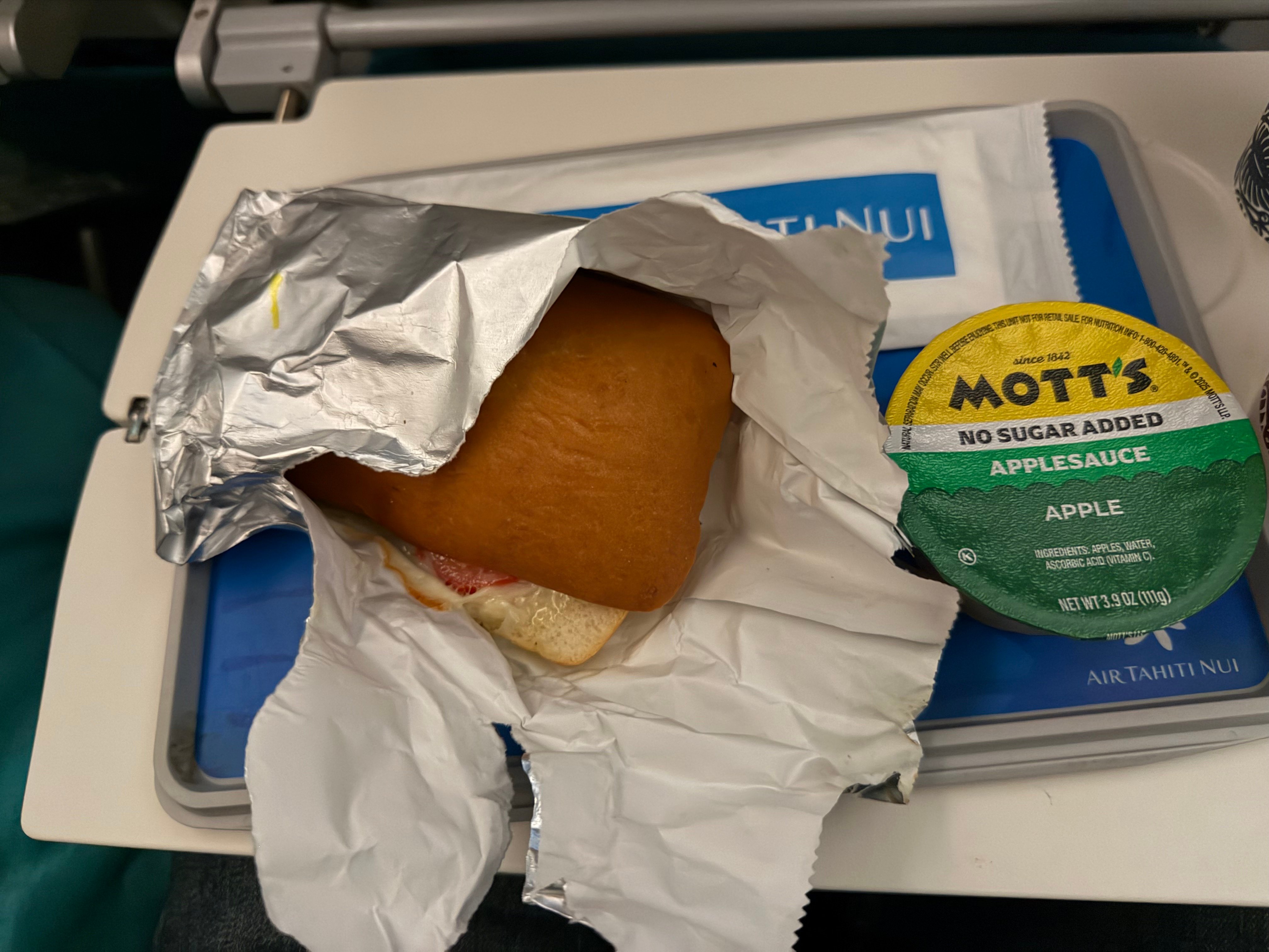 Warm pork sandwich and applesauce served before arrival on Air Tahiti Nui.