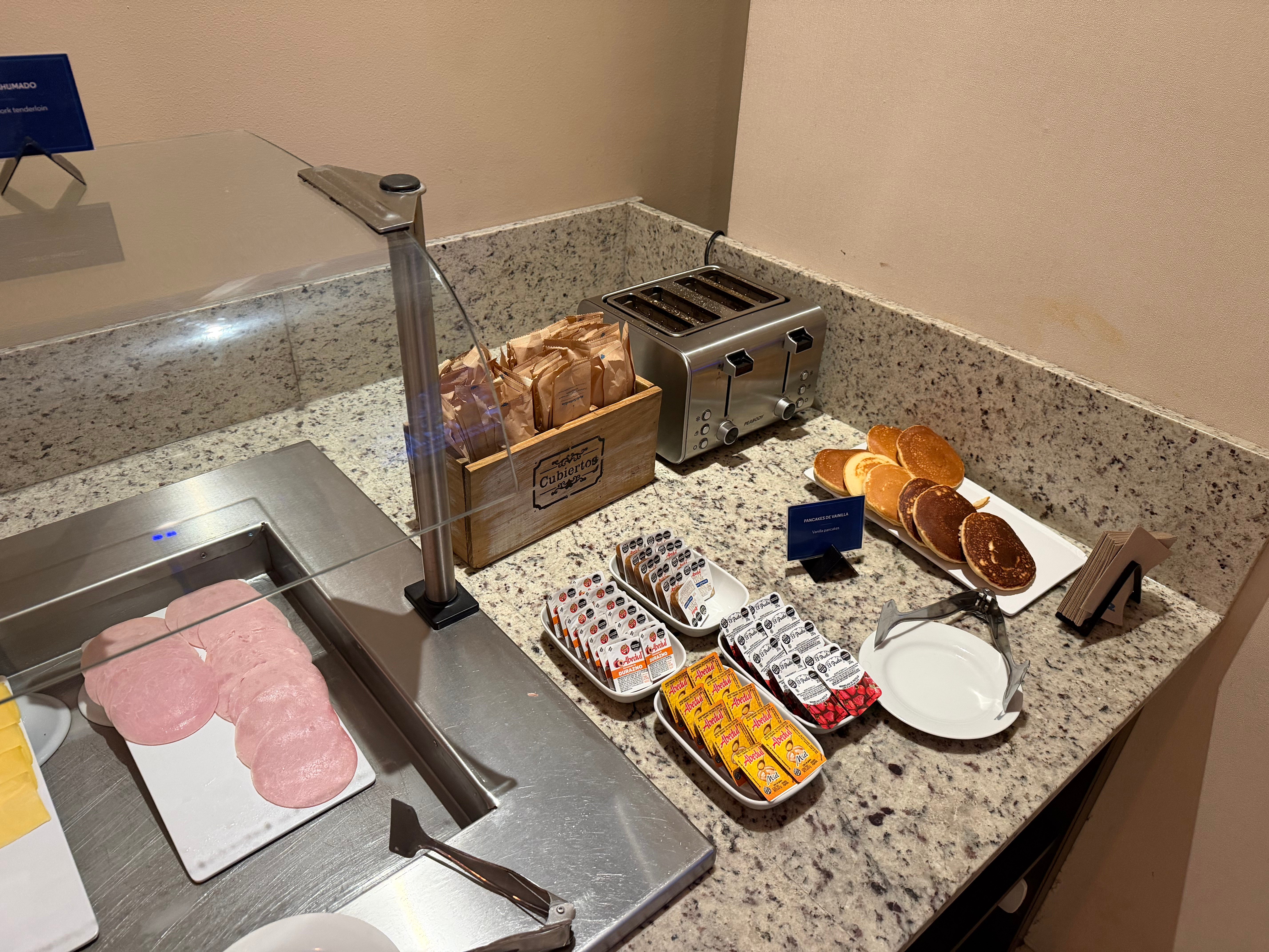 Cold cuts, spreads, and toaster at the Condor Lounge breakfast buffet.