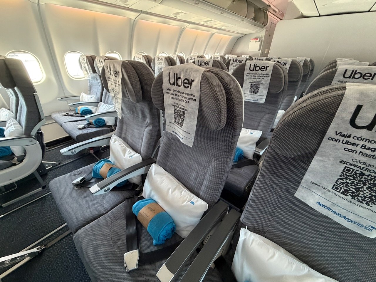 Aerolíneas Argentinas economy seat with headrest cover, pillow, and blanket.