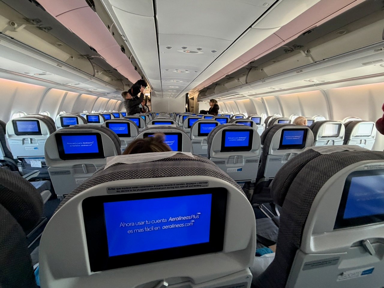 Aerolíneas Argentinas A330 economy cabin during boarding with seatback screens on.