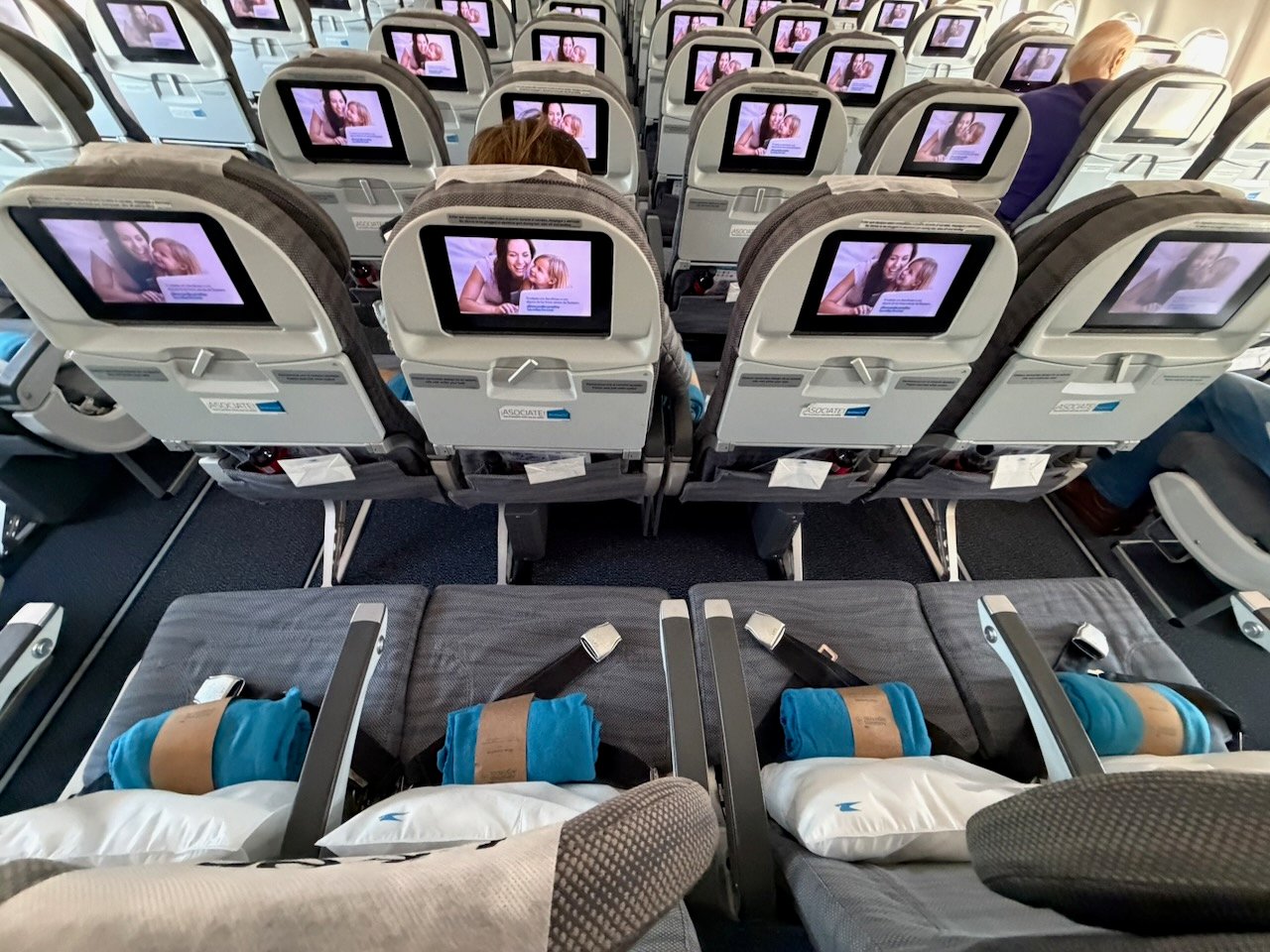Rows of economy seats and IFE screens during boarding on the Aerolíneas Argentinas A330.