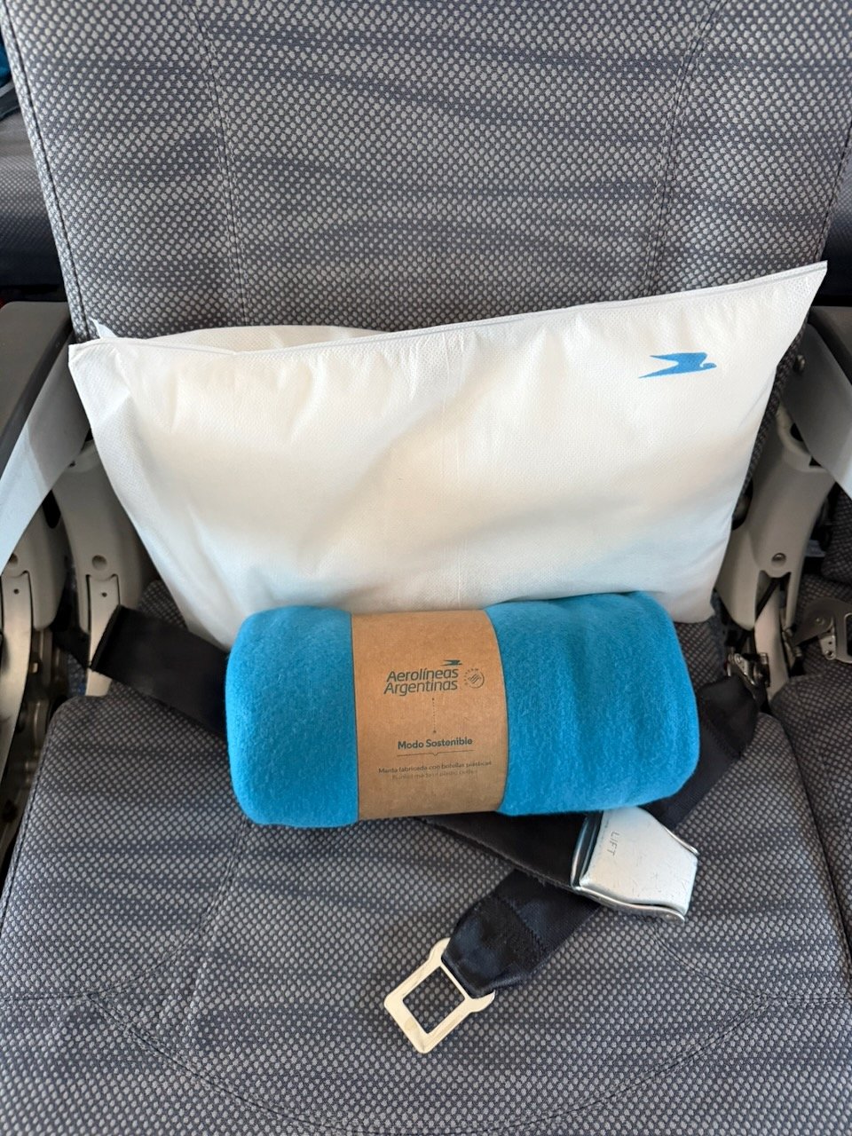 Pillow and blanket placed on an Aerolíneas Argentinas economy seat.