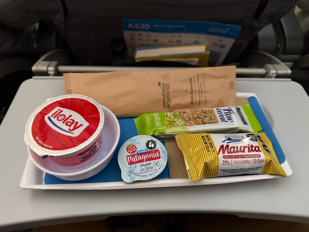 Aerolíneas Argentinas economy snack tray with yogurt, crackers, cream cheese, and cereal bar.