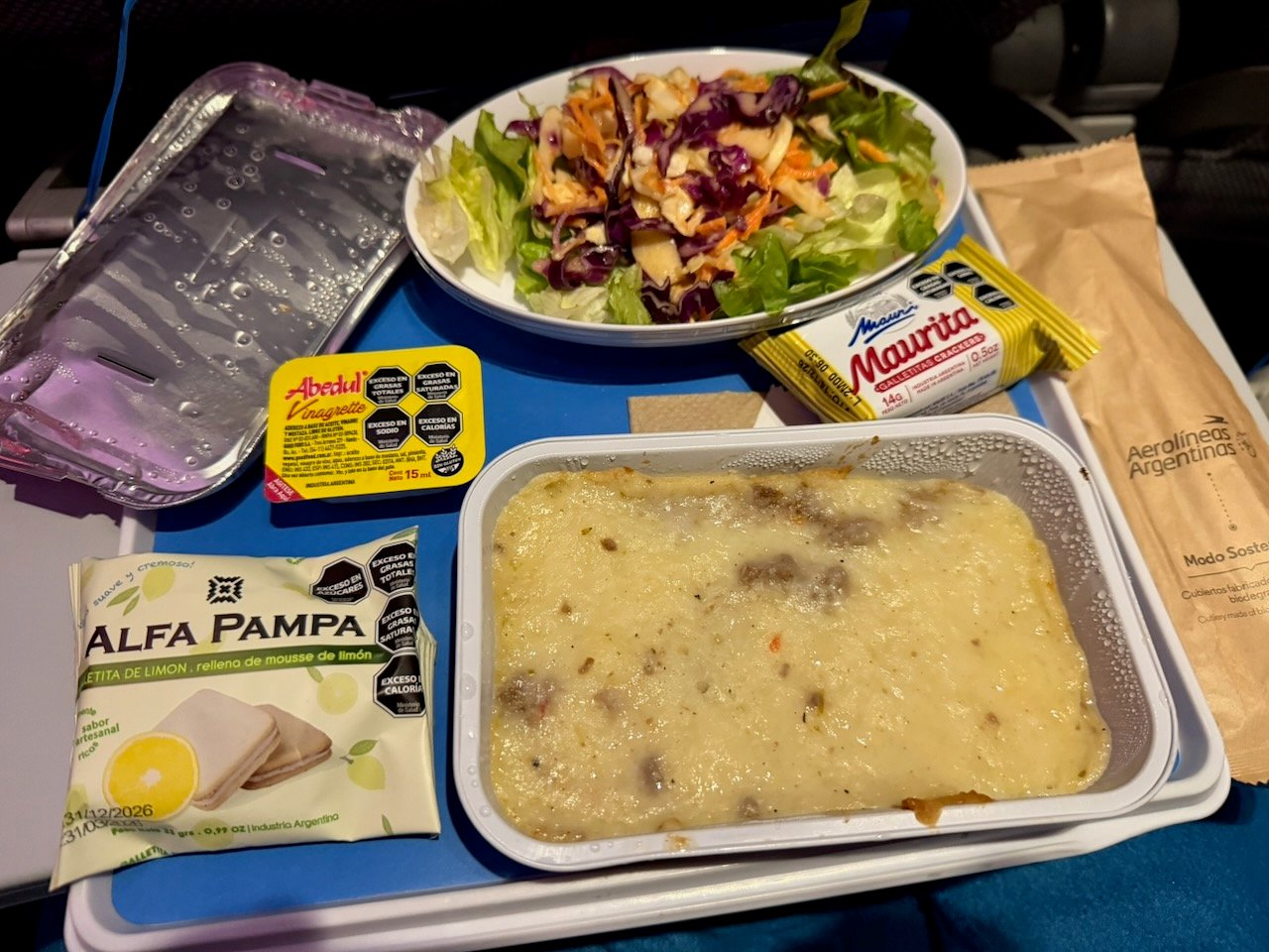 Aerolíneas Argentinas economy dinner tray with hot main course and side salad.