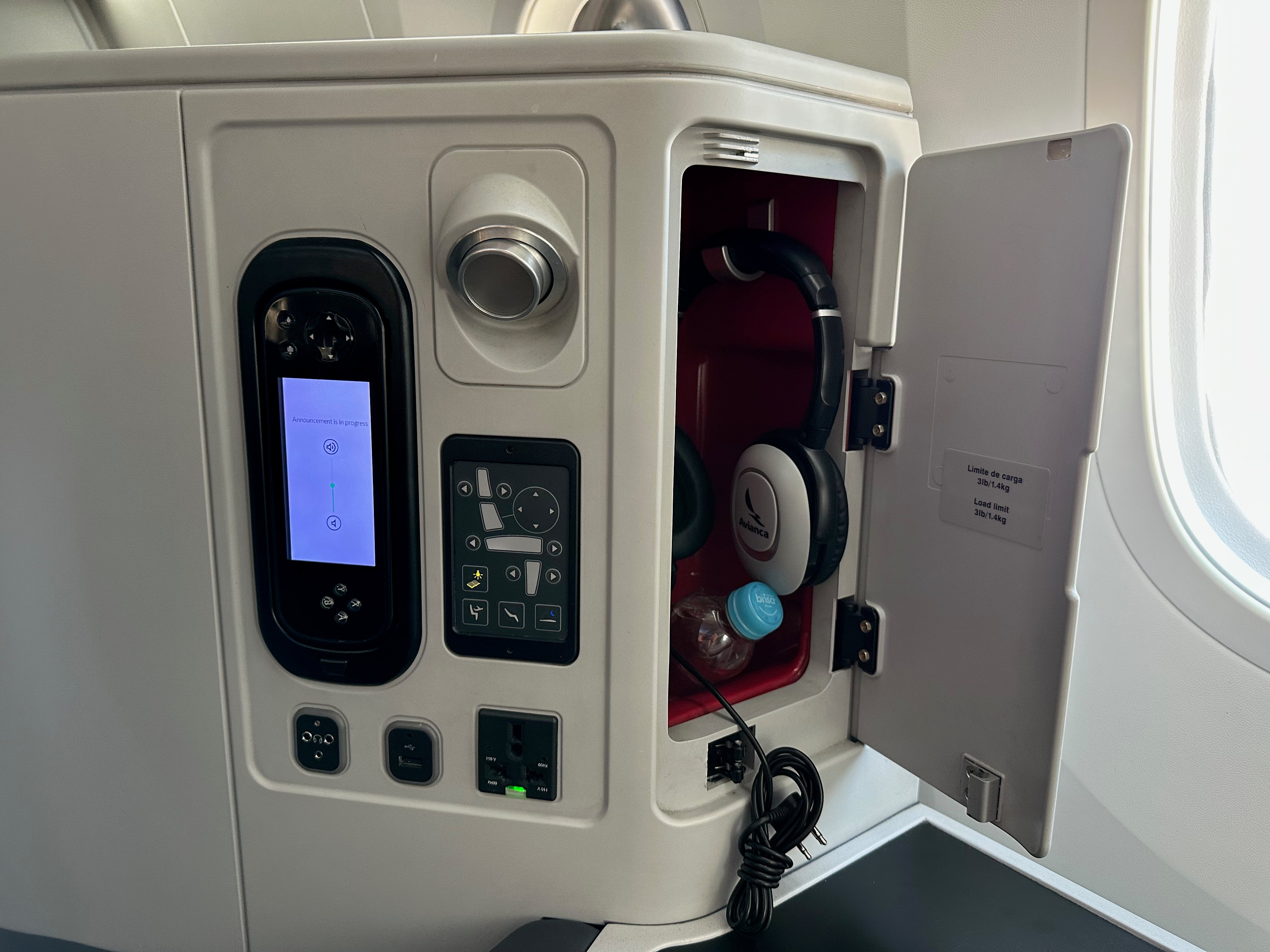 Seat controls, remote, power sockets, and storage compartment with headphones.