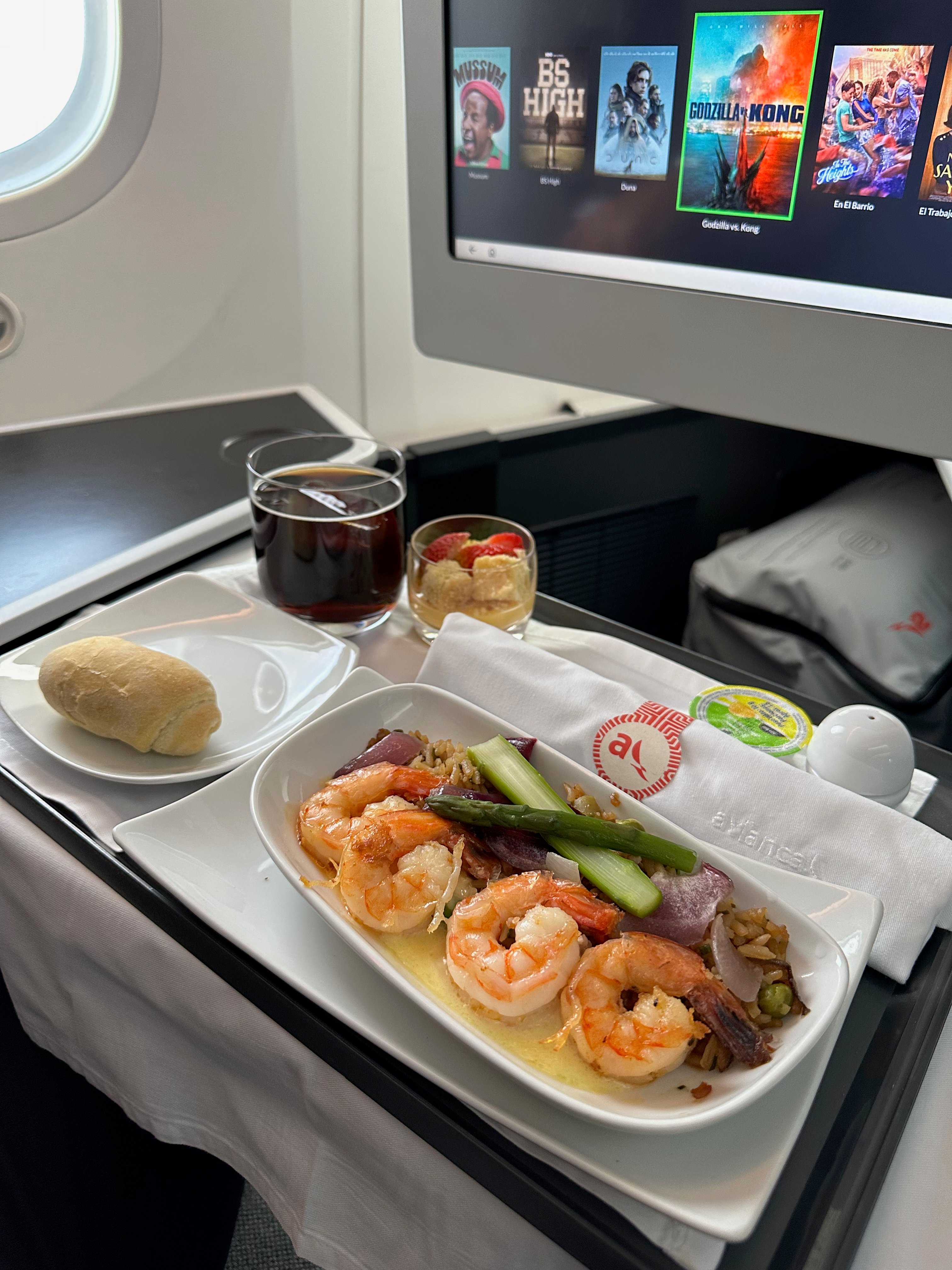 Shrimp with rice and vegetables, bread, and dessert on a Business Class meal tray.