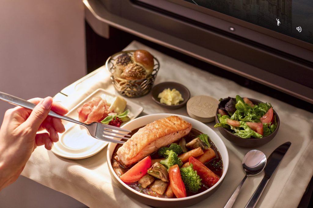Avianca INSIGNIA meal with salmon, vegetables, salad, and bread served on a tray table.