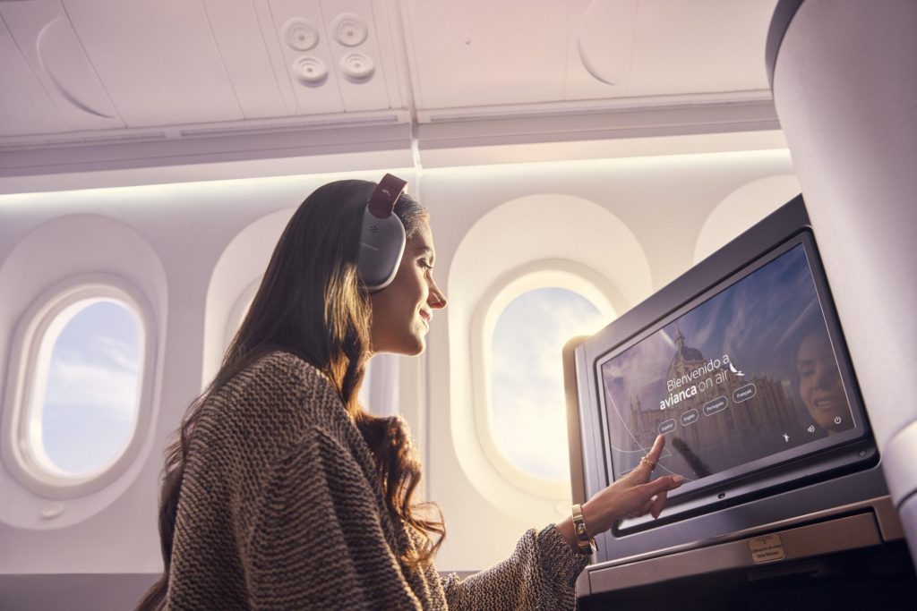 Passenger using the Avianca entertainment screen while wearing headphones.