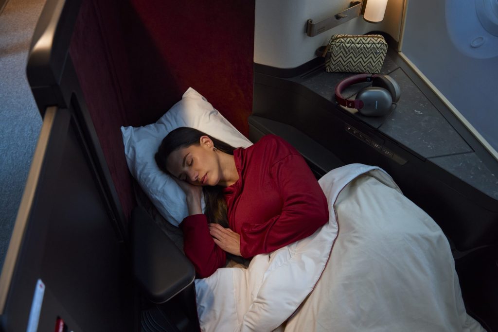 Passenger resting under a duvet in an Avianca INSIGNIA seat that reclines into a flat bed.
