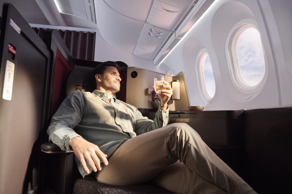 Passenger reclining in an Avianca INSIGNIA window seat with a drink.
