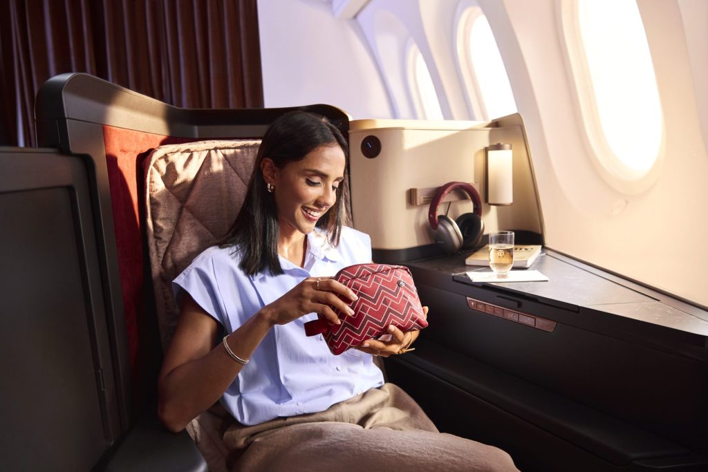 Avianca INSIGNIA passenger holding a patterned amenity kit beside a window seat.