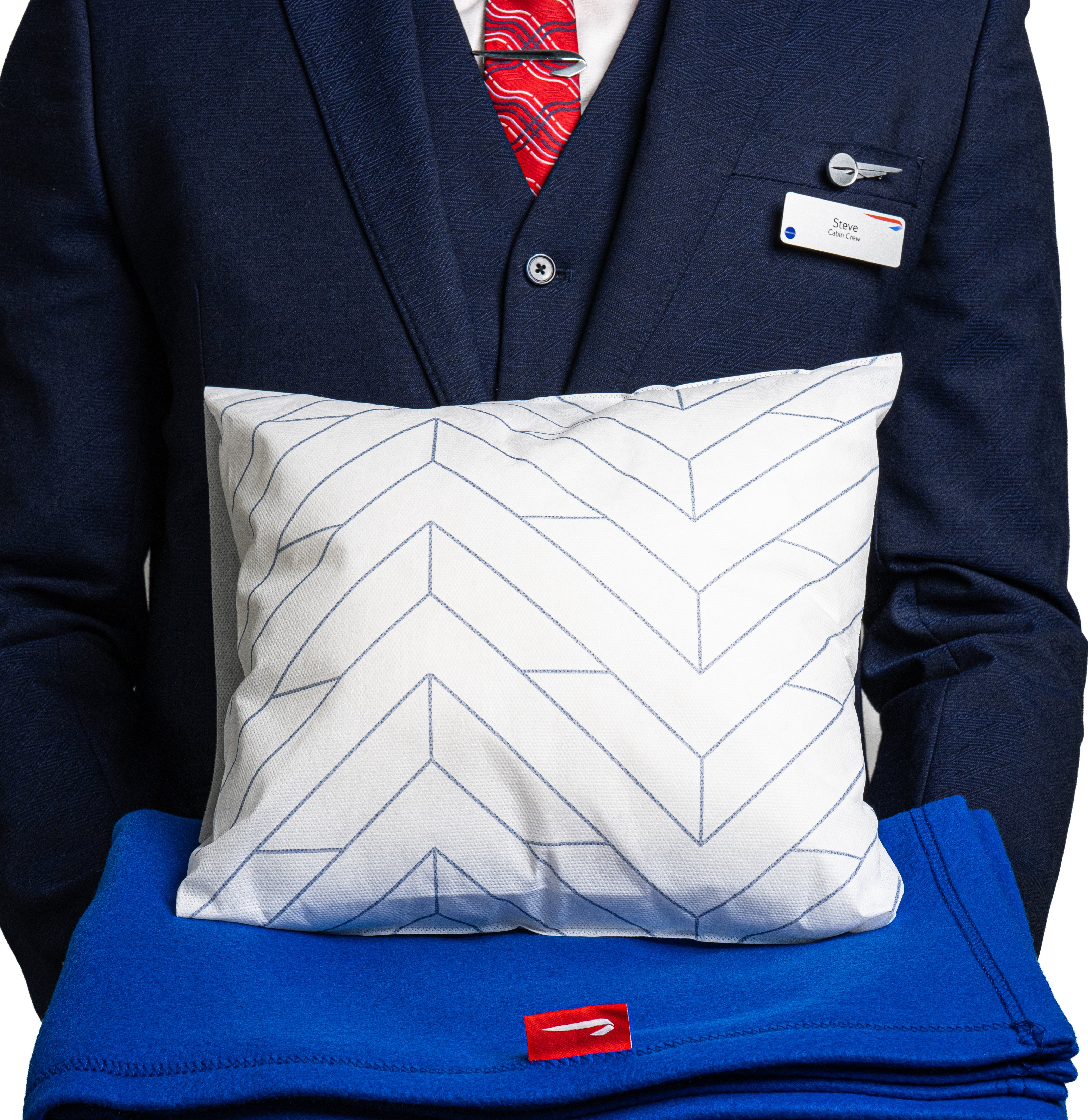 British Airways crew member holding the new blue Economy blanket and patterned pillow.