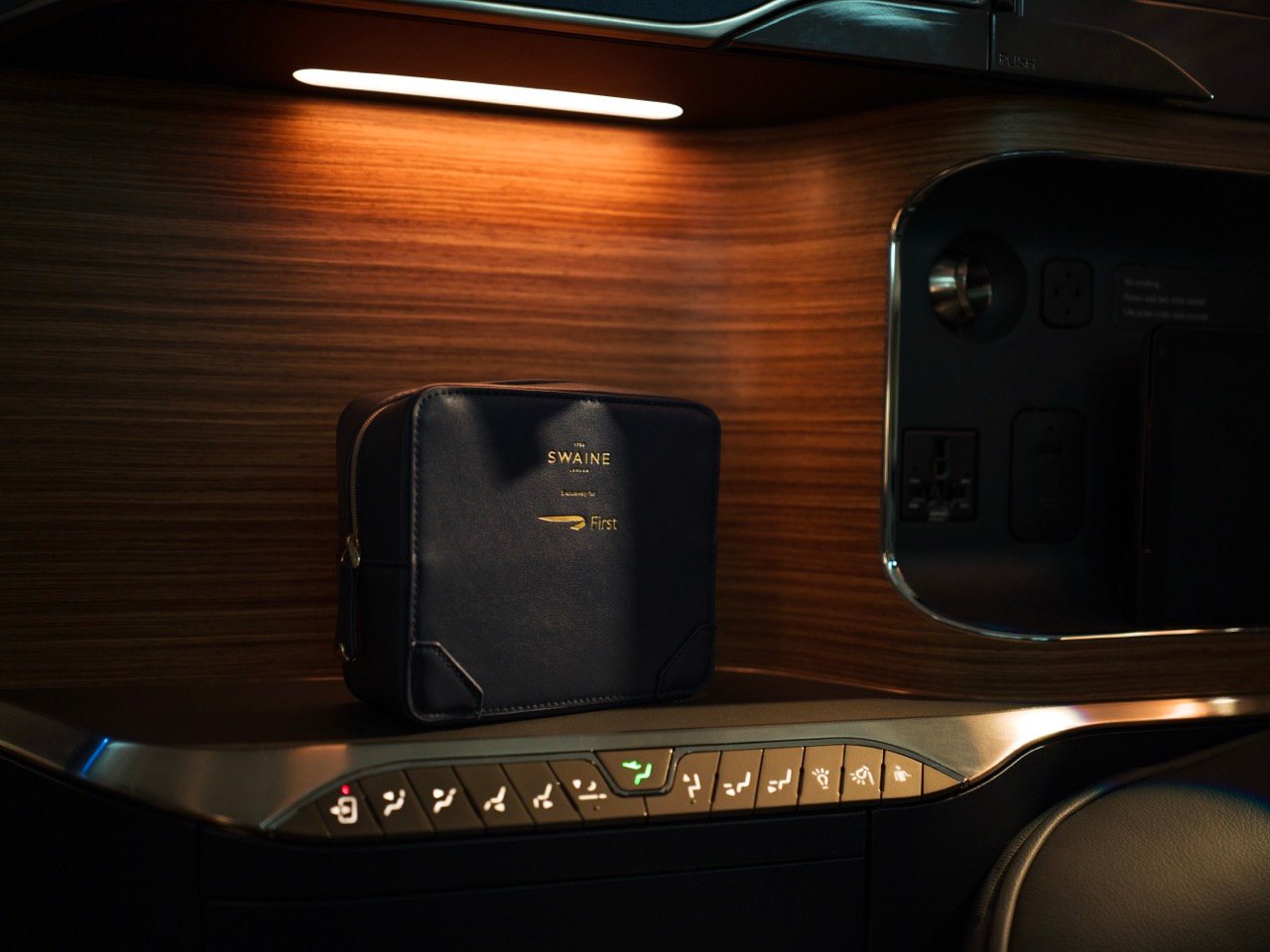 Swaine First amenity kit displayed in a wood-finished storage compartment.
