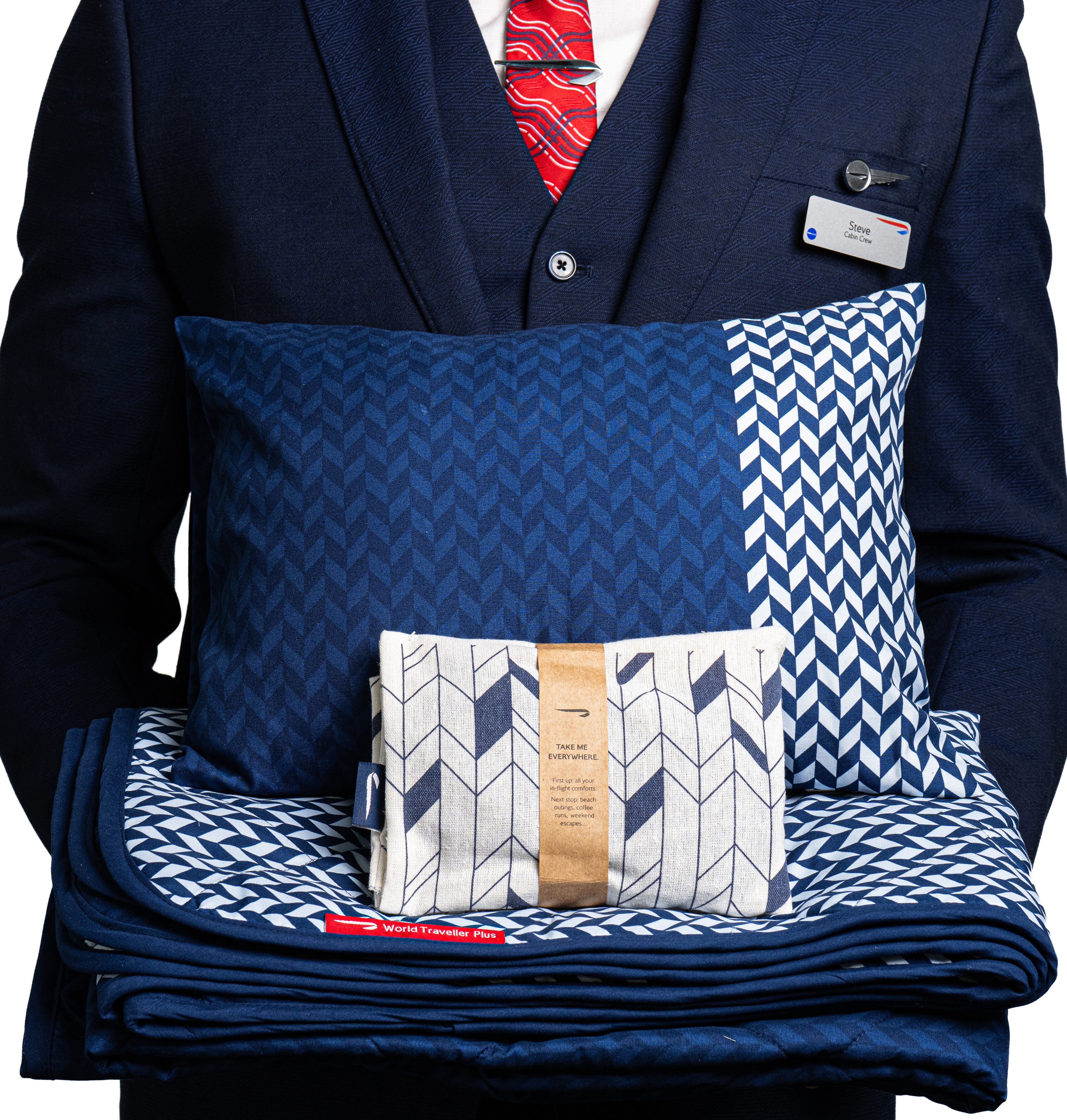 Crew member holding the new World Traveller Plus bedding, pillow and amenity kit.