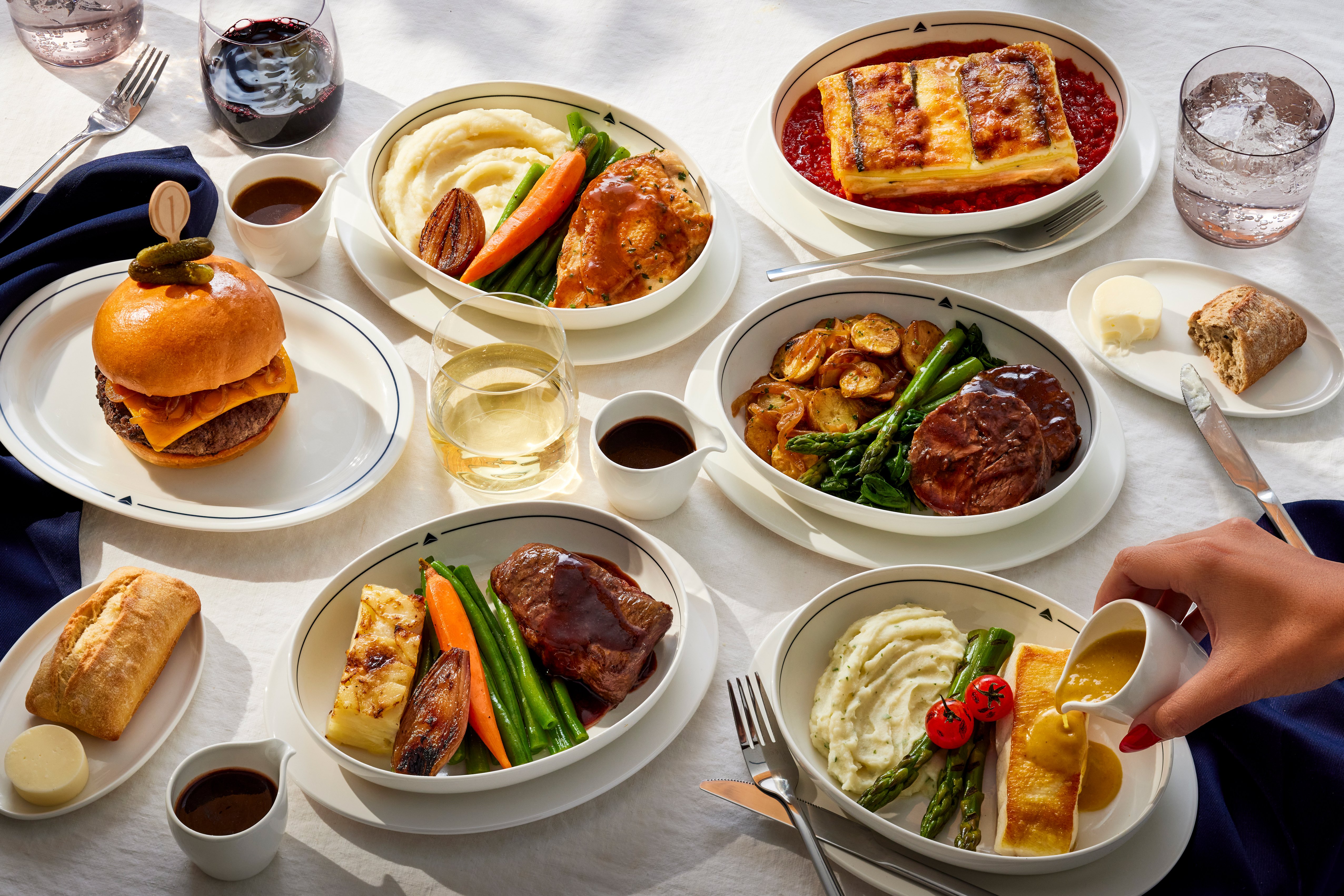 Selection of Delta One meals, including a burger, fish, and other main courses served on white tableware.