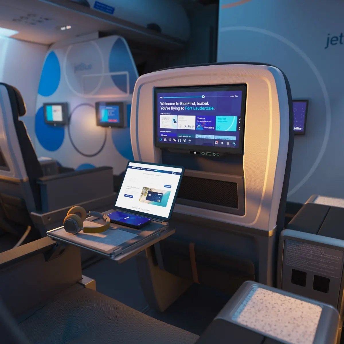 JetBlue BlueFirst seat with a seatback screen, personal devices, power outlets, and a large center console.